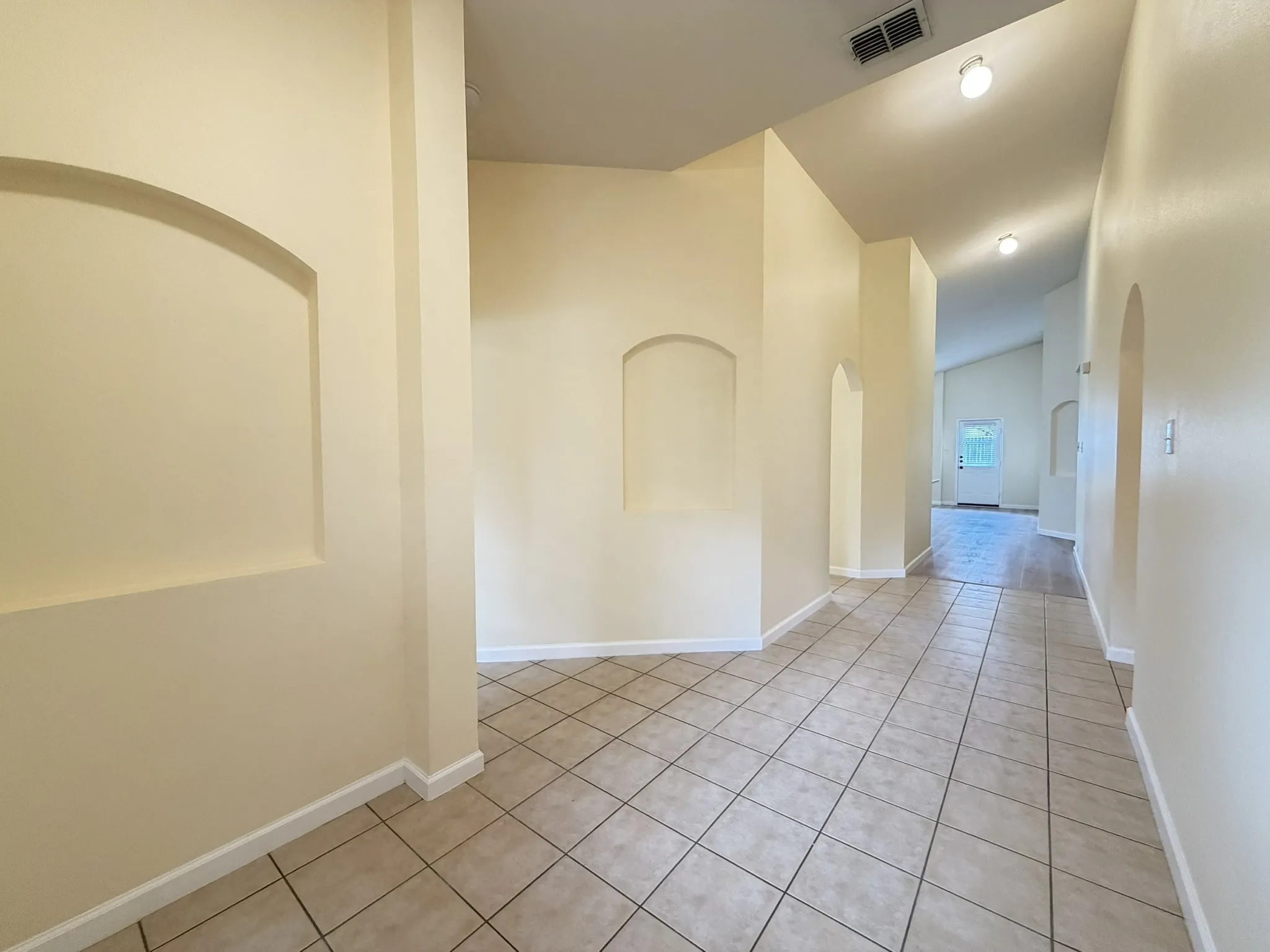 Interior space featuring ceramic tile flooring, vaulted ceilings, recessed wall niches, and arched entryways