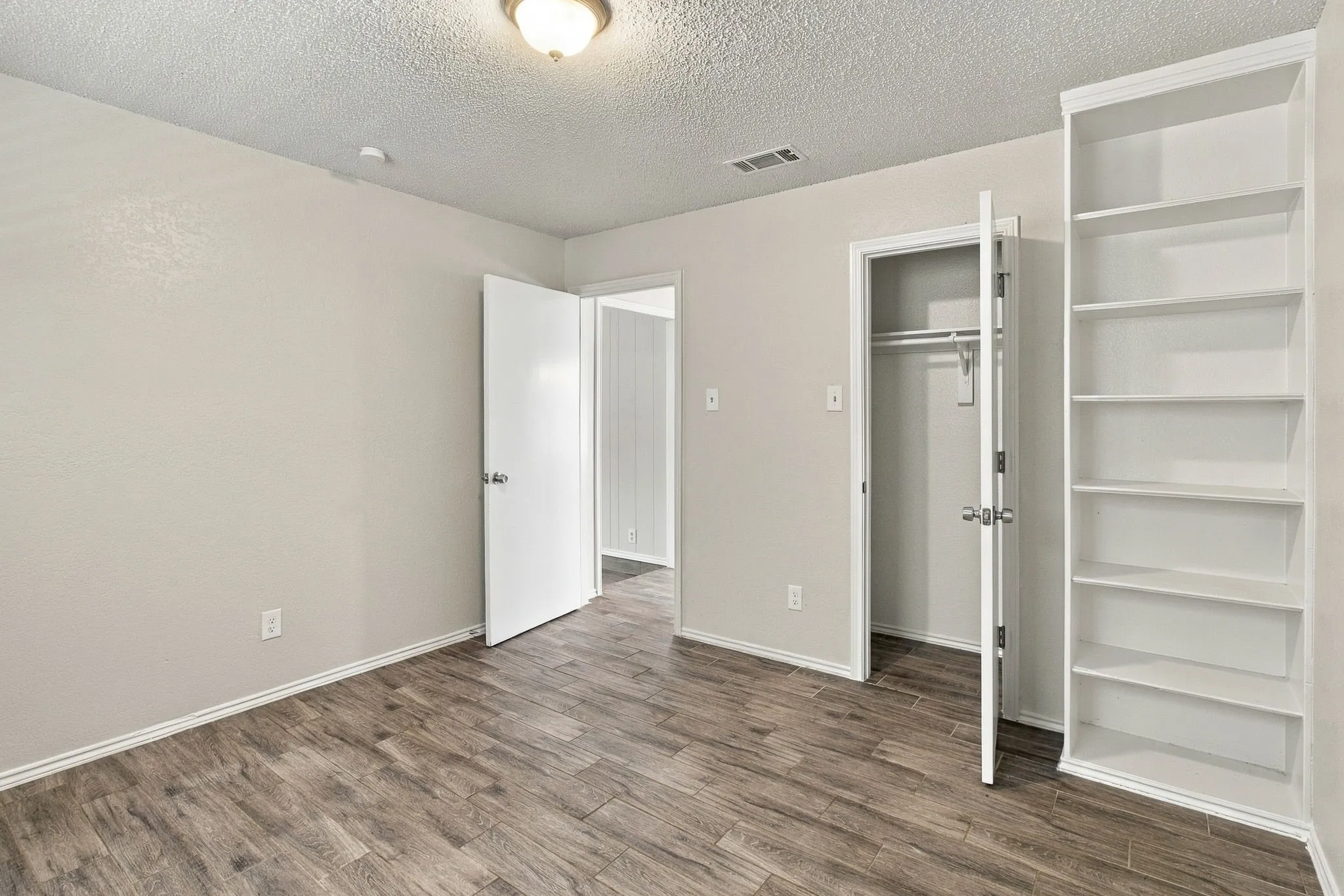 Wood-finish flooring, built-in shelving, and neutral wall color