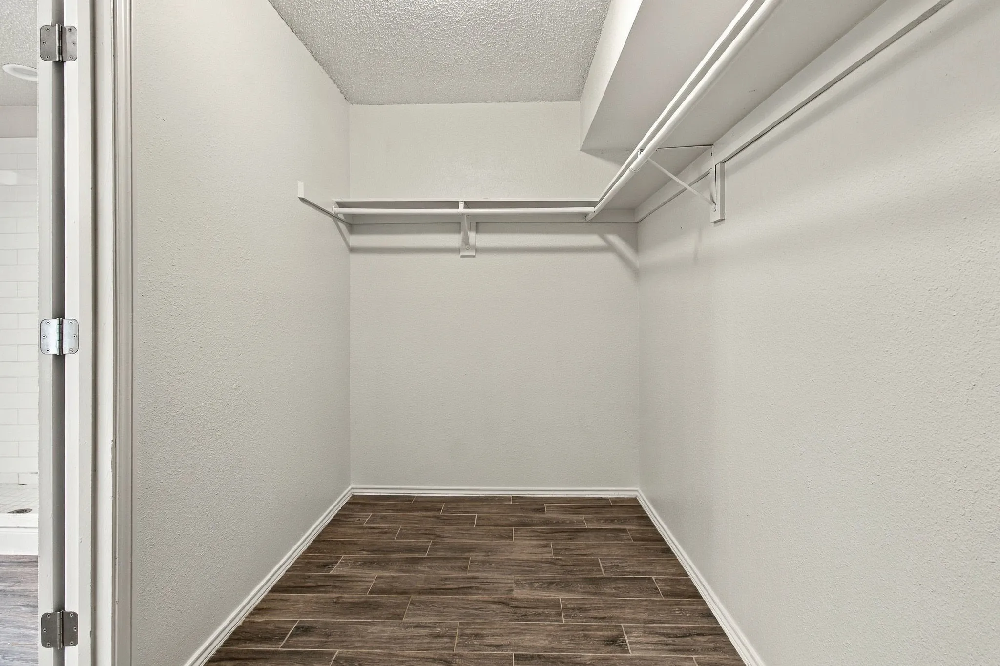 Walk-in storage space featuring wood-finish flooring and dual-level metal shelving