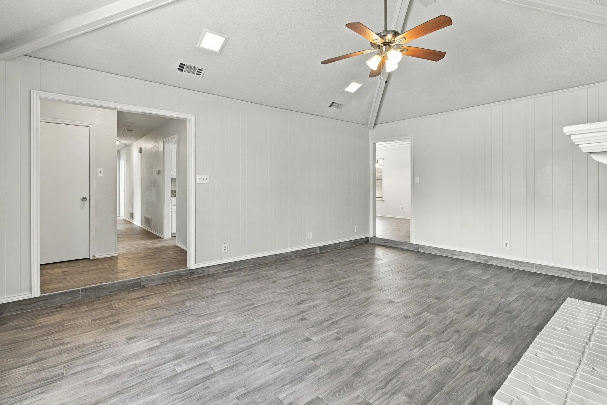 Vaulted ceiling featuring recessed lighting and a central ceiling fan, plank-style flooring, and vertical panel wall detailing