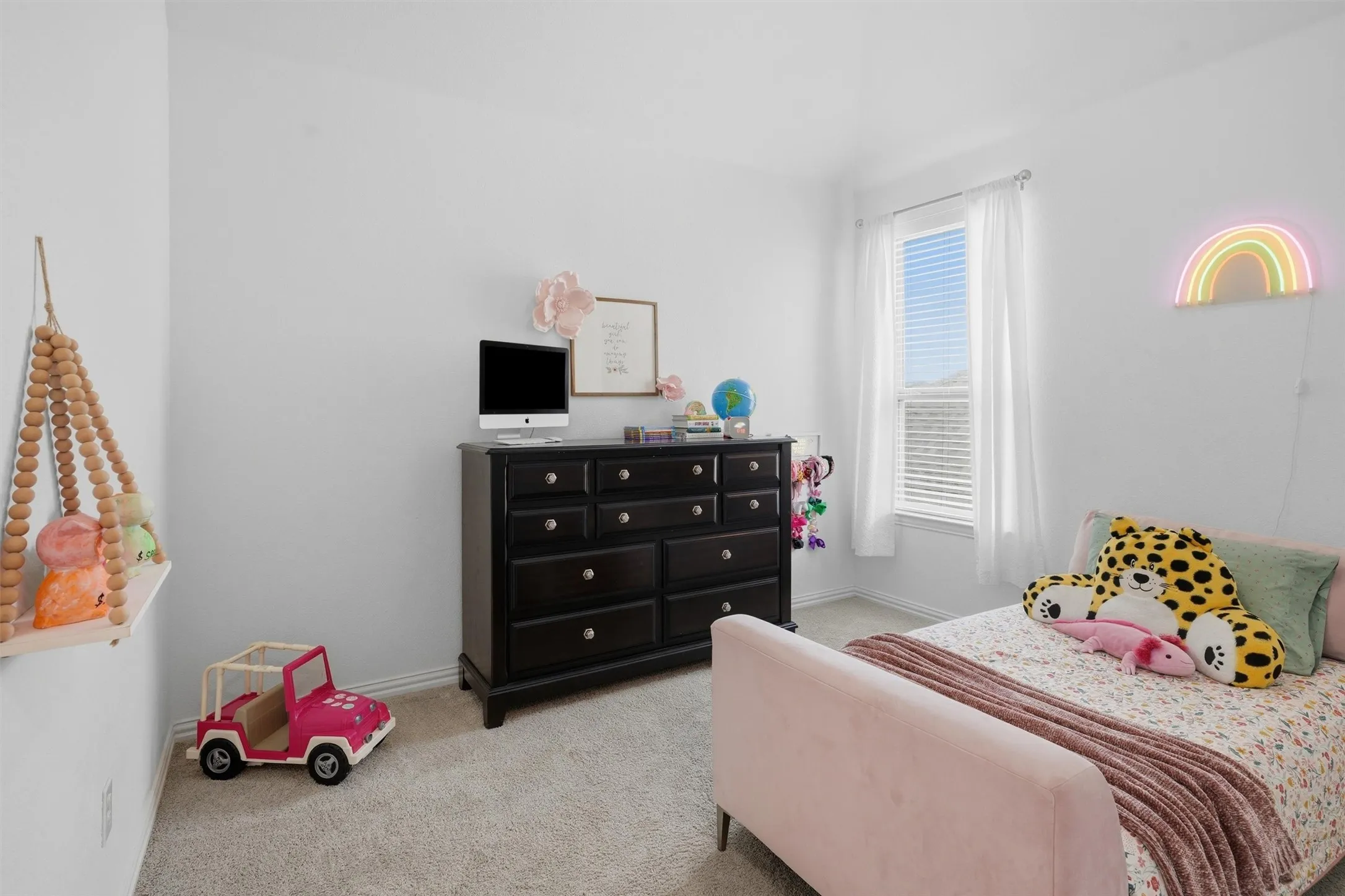 Bright and cheerful secondary bedroom featuring soft neutral carpeting, clean white walls, and a large window for natural lighting. Generously sized with ample room.