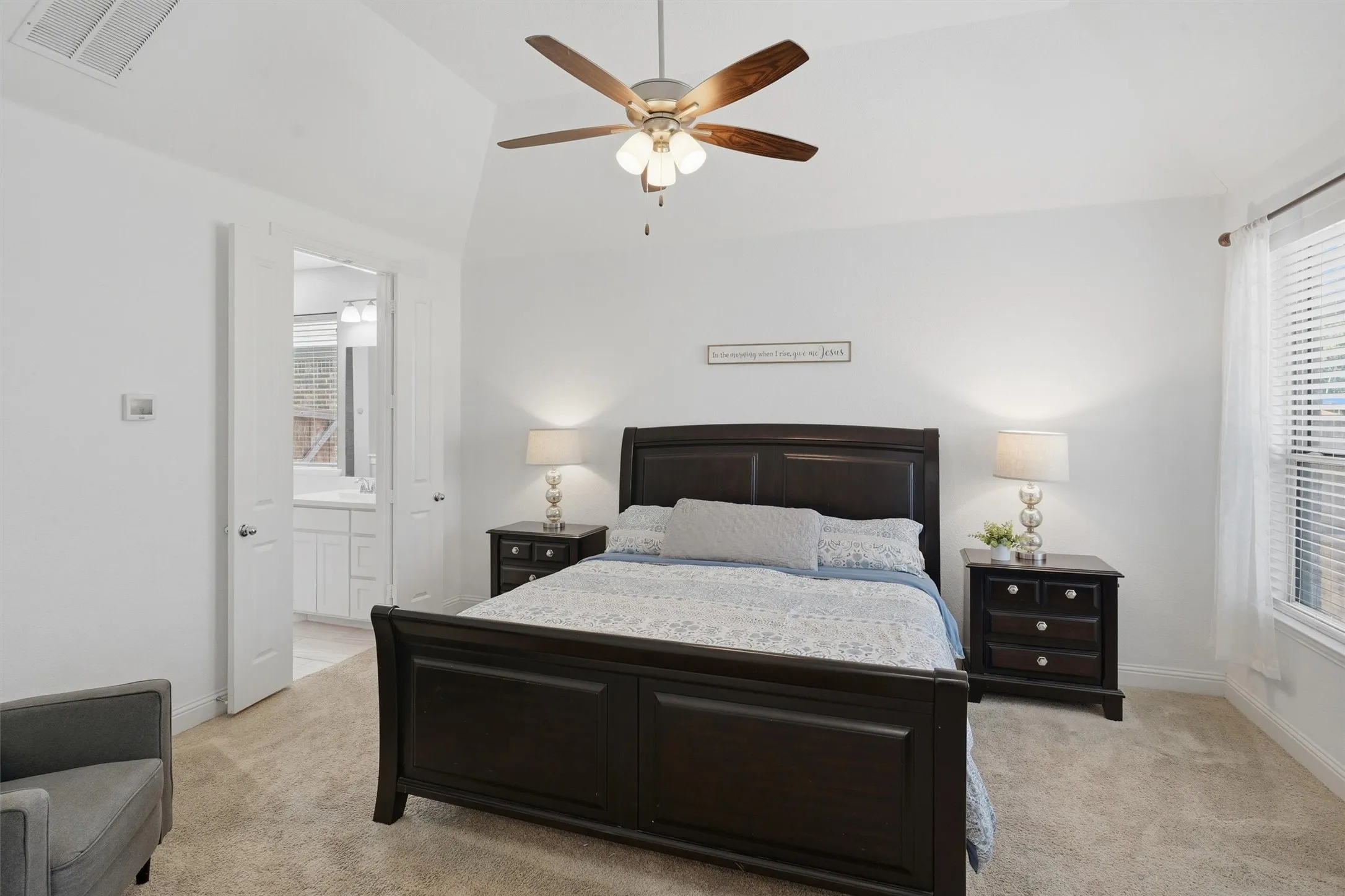 Spacious primary bedroom featuring high vaulted ceilings, large windows for natural light, and direct double door access to the en-suite bathroom.