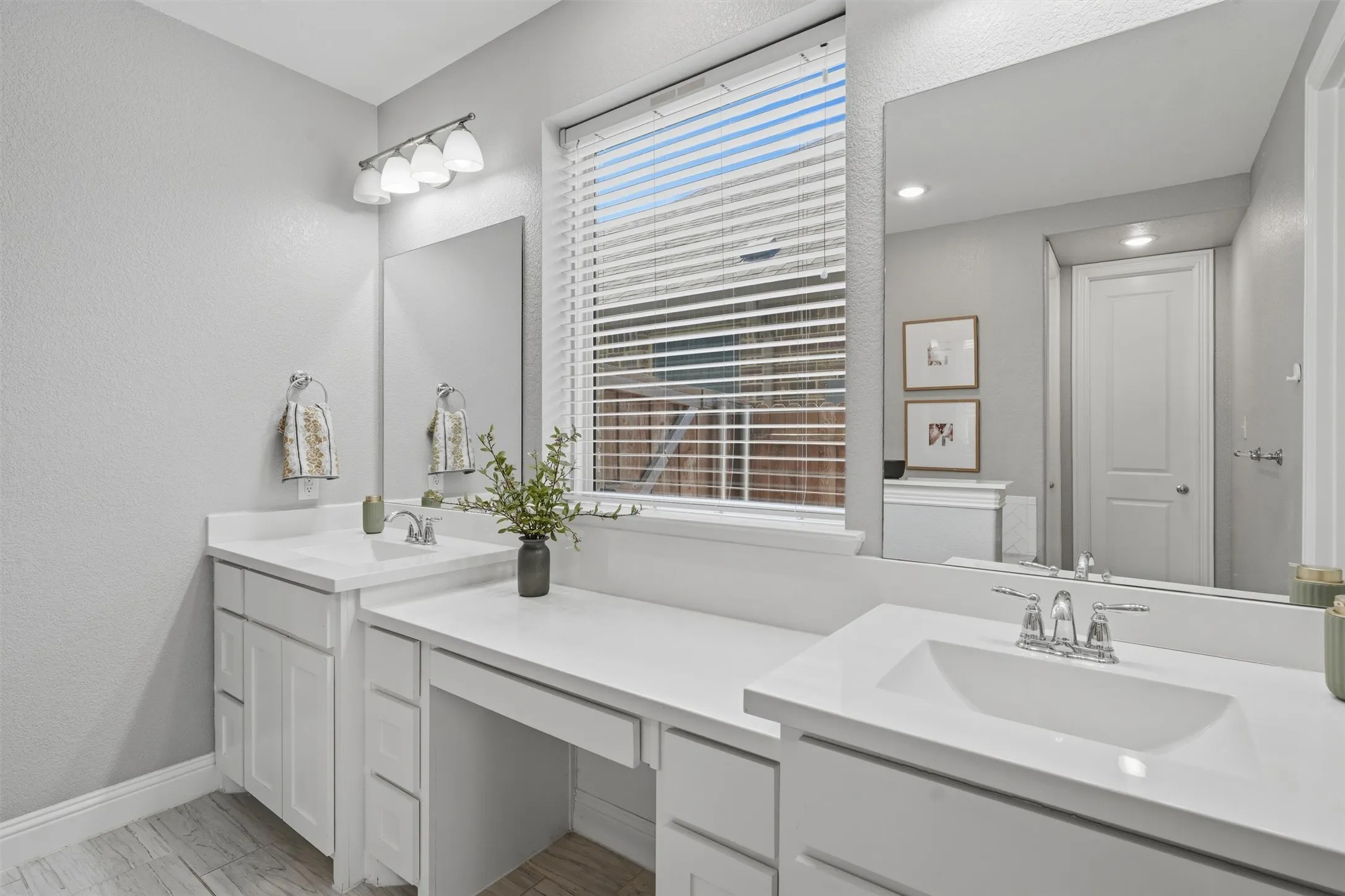 Focused view of the primary bath dual vanities featuring generous counter space, and a central seated vanity area. Designed to streamline busy morning routines with ample storage and separate wash stations.
