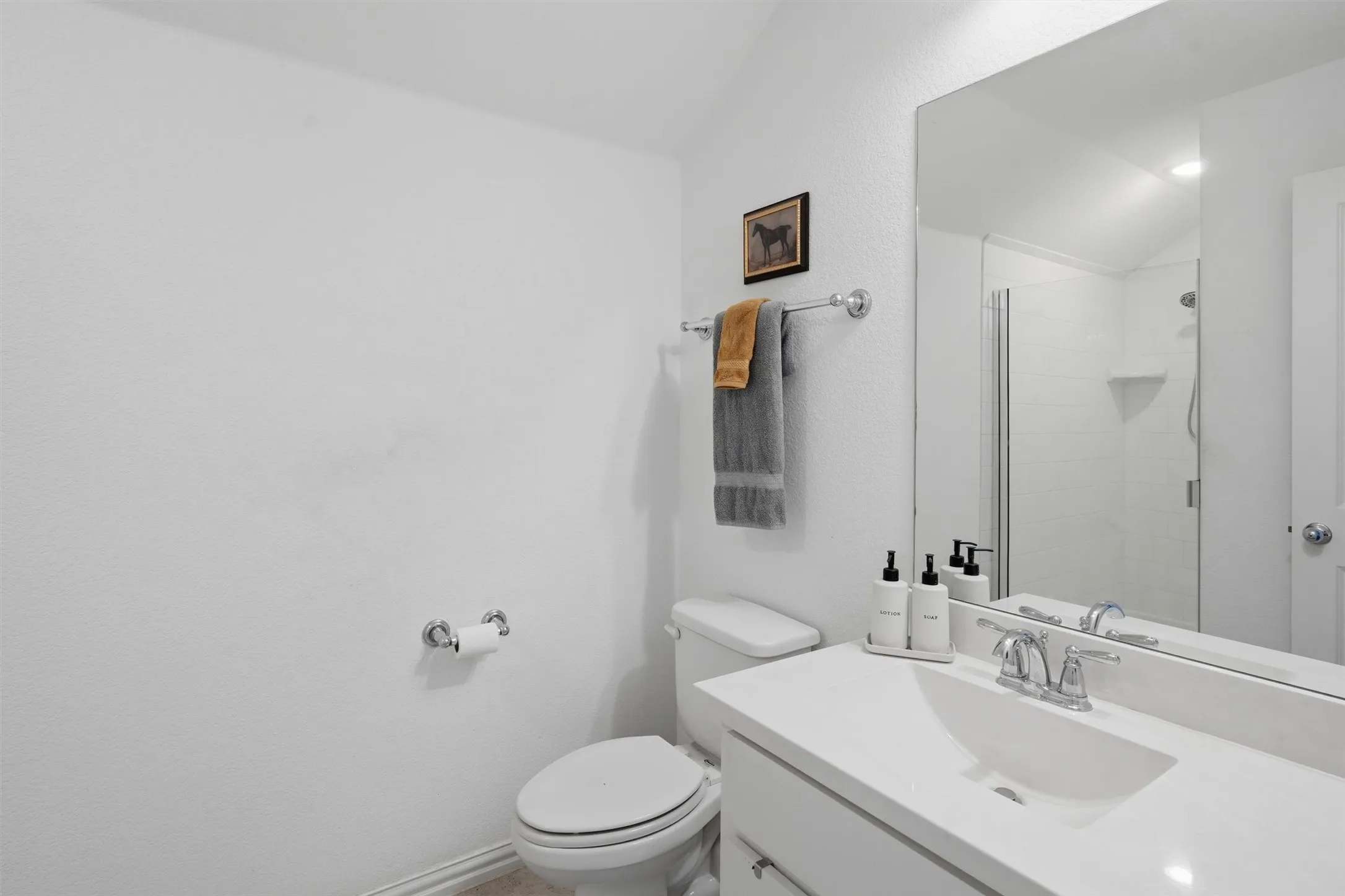 Clean secondary bathroom featuring a single white vanity, bright modern fixtures, and a glass-enclosed step-in shower. Ideal setup for guests or family members seeking convenient, private accommodations.
