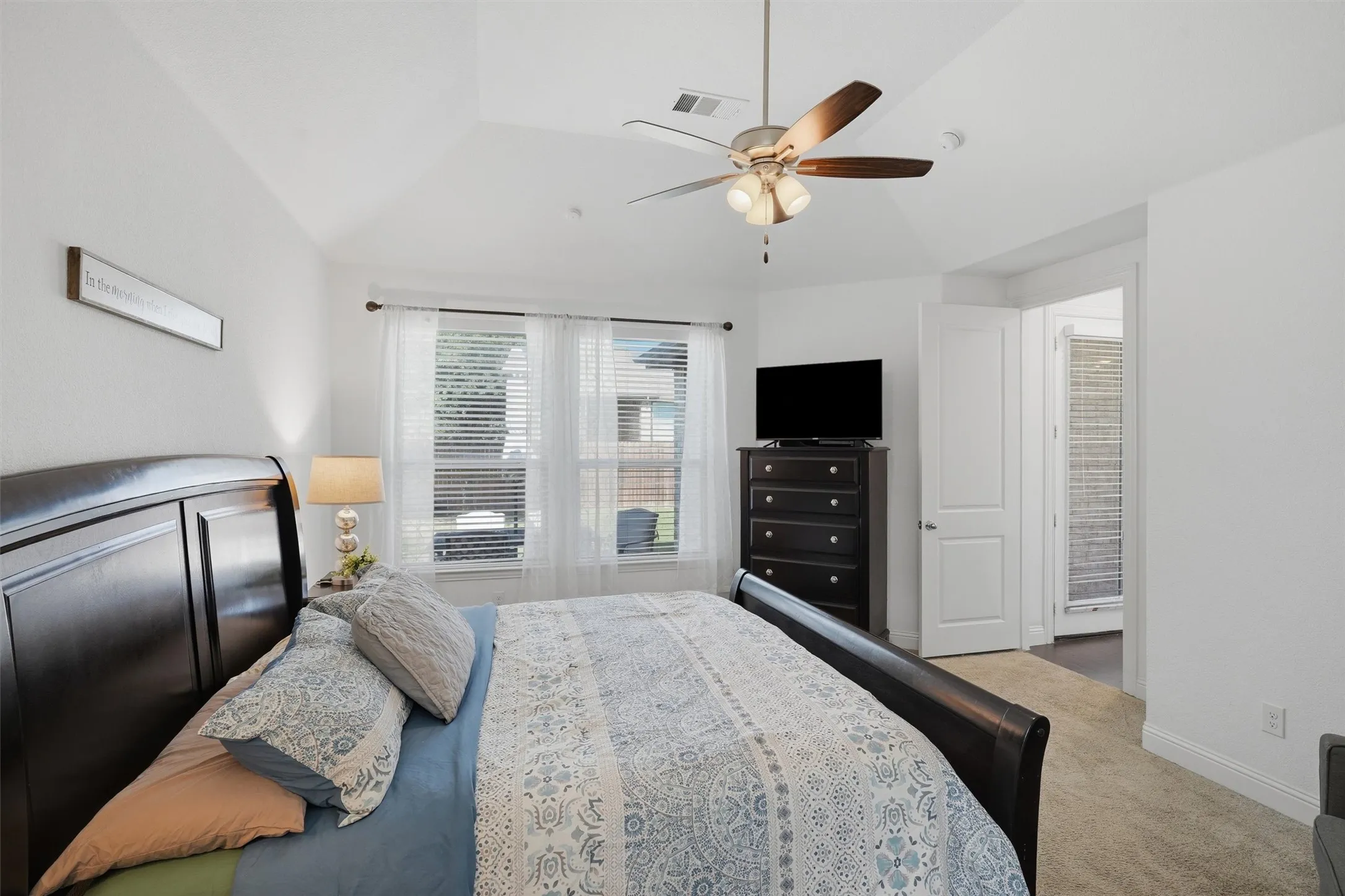Alternate angle of the primary suite highlighting the large window wall and tray ceiling design. Features a bright entry hall connection and plenty of room for oversized bedroom furniture.