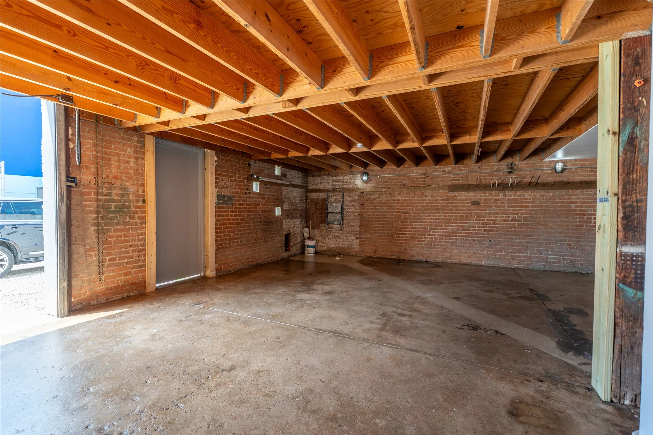 Exposed brick walls, open wood-beam ceiling, and concrete flooring
