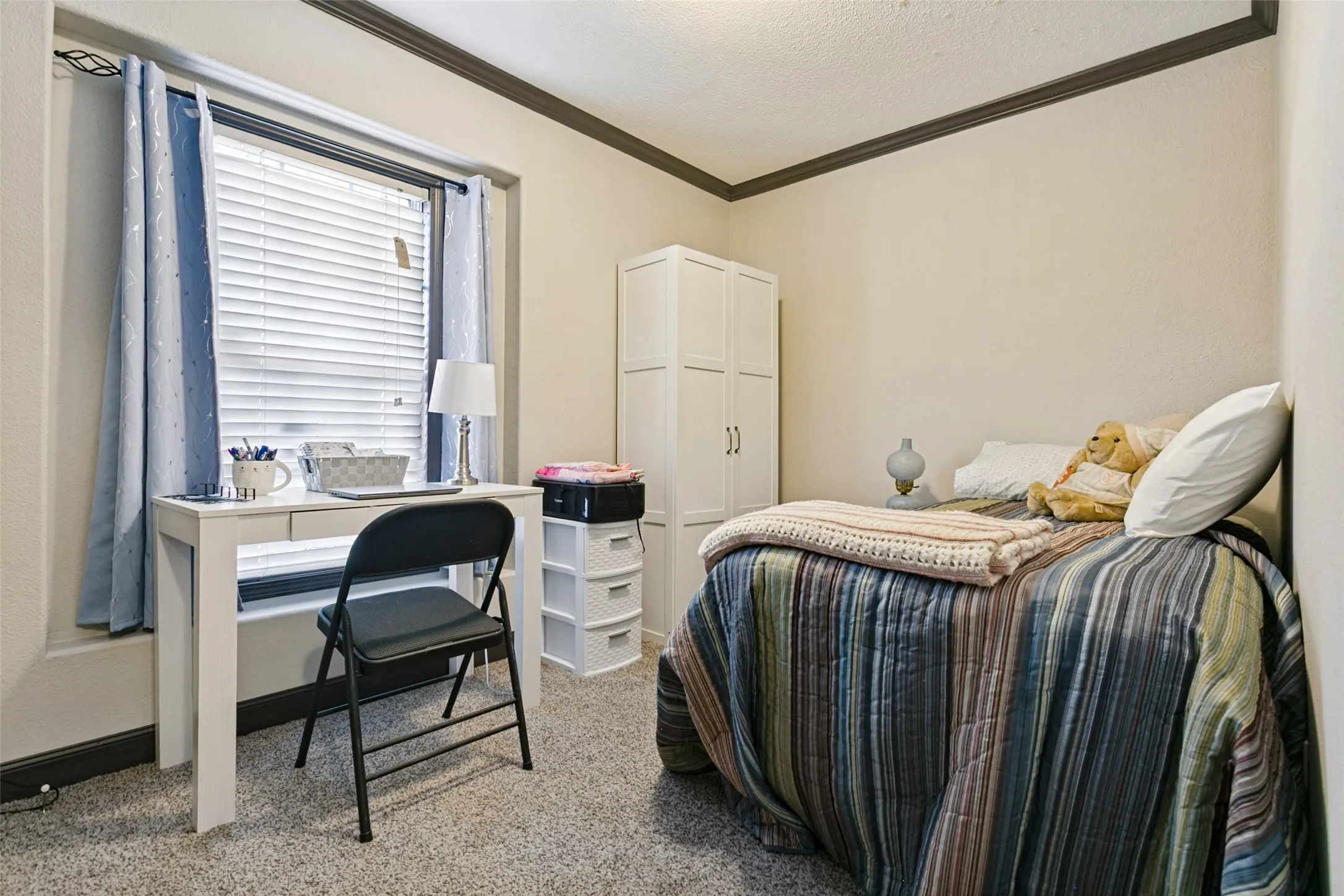 Neutral-toned interior featuring wall-to-wall carpeting, window with slatted blinds, and crown molding