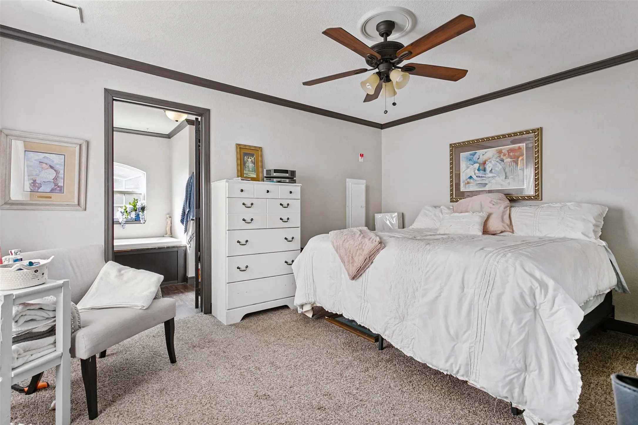 Room featuring neutral wall tones, decorative crown molding, carpeted flooring, and a ceiling fan with integrated lighting