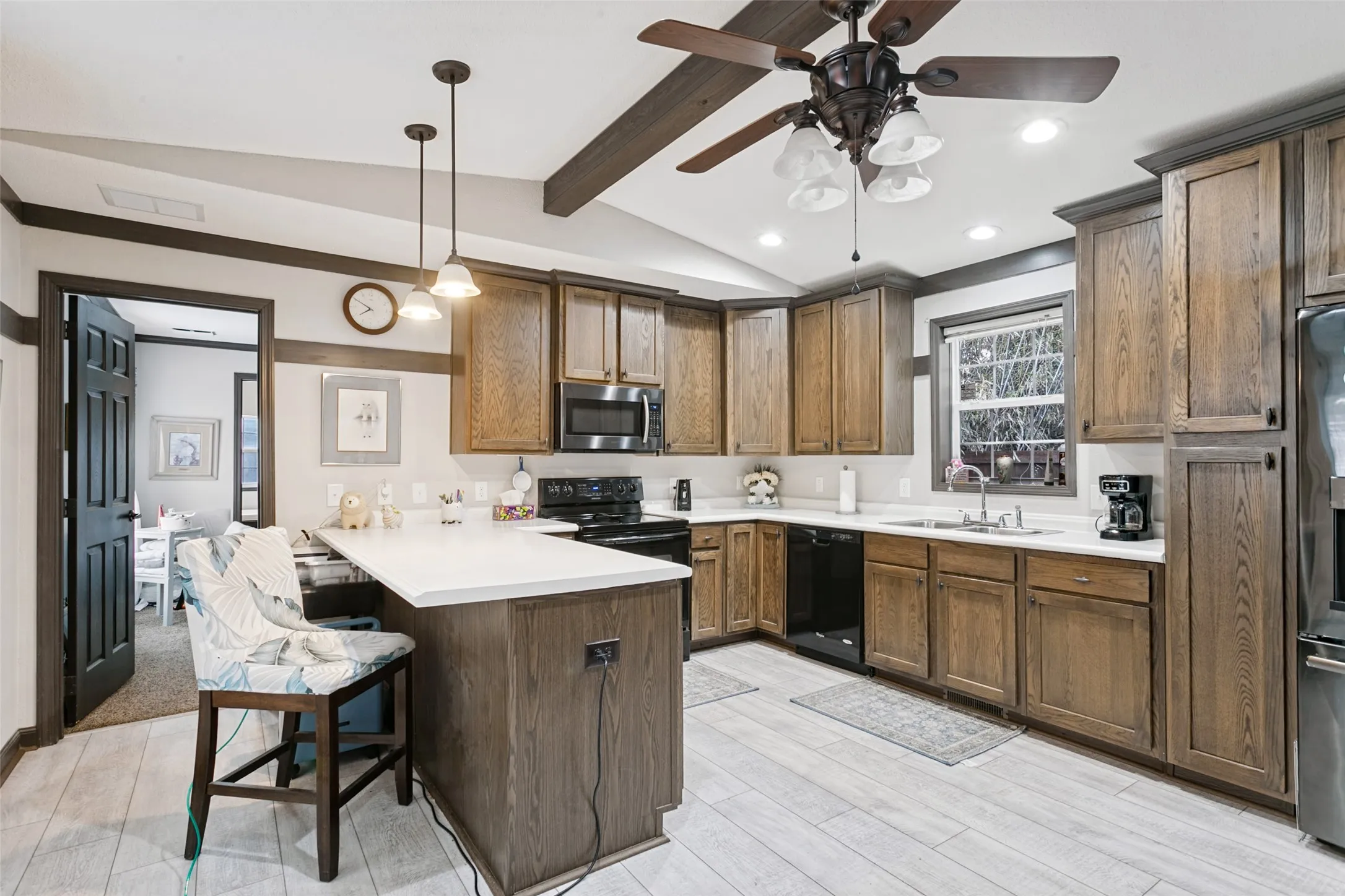 Kitchen featuring stained wood cabinetry, stone-surface countertops, wood-finish ceiling beams, tile flooring, and pendant lighting