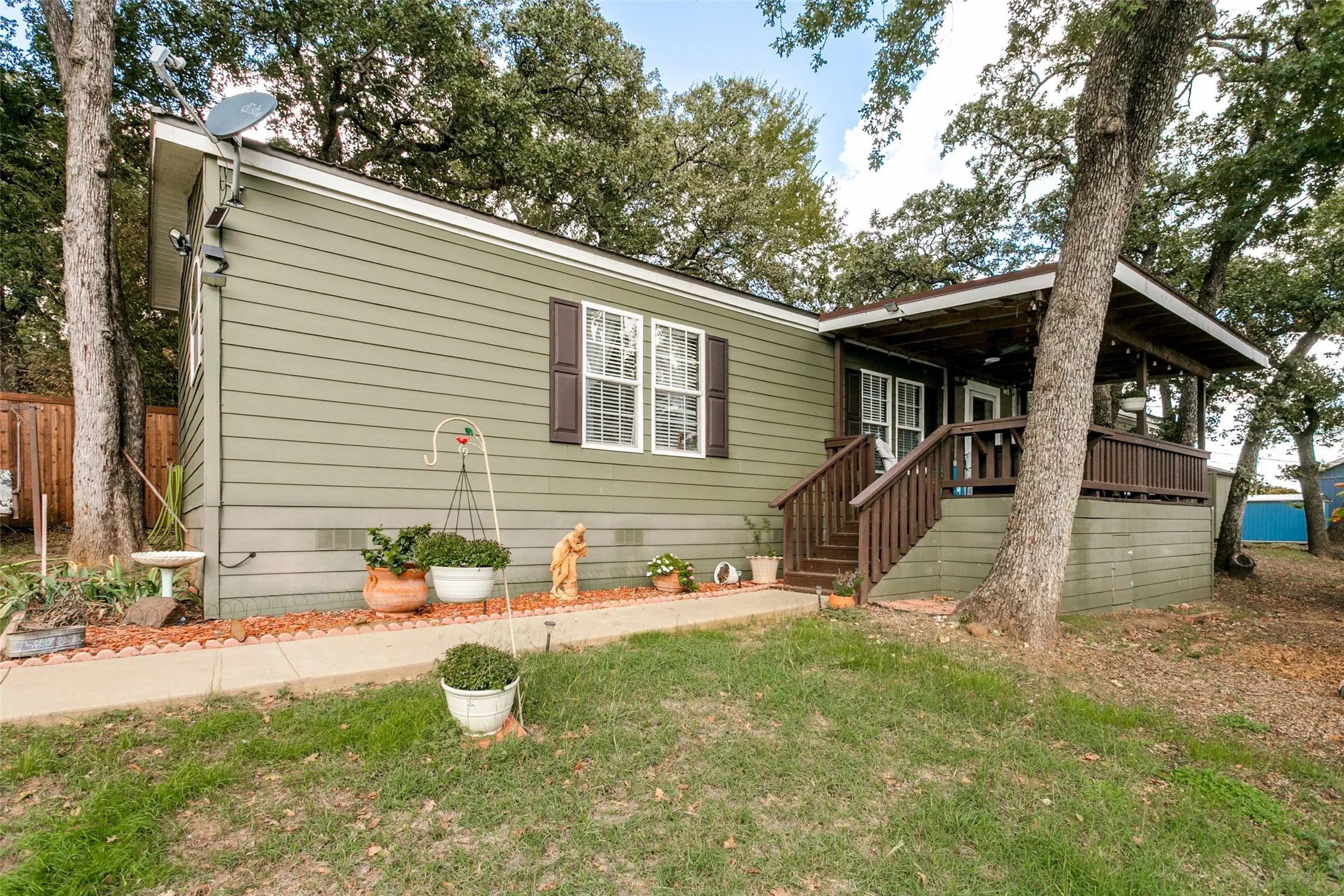 Exterior featuring horizontal lap siding, a covered porch with wooden railings, and mature trees on a wooded lot