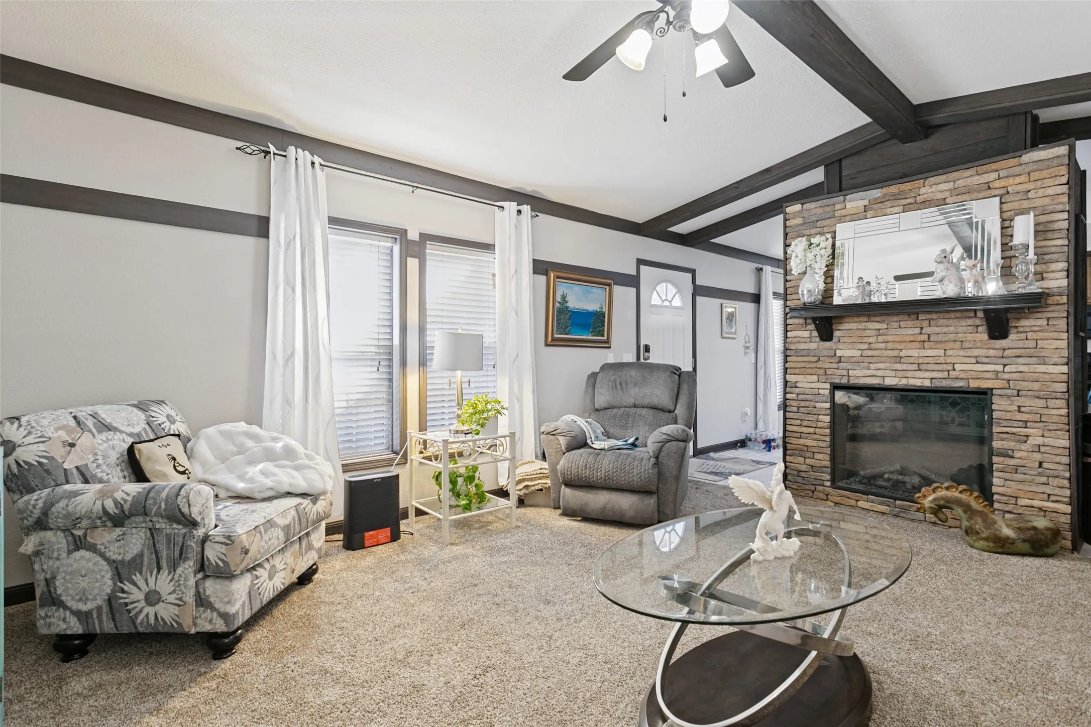 Floor-to-ceiling stone-faced fireplace with a built-in mantle, exposed wood ceiling beams, and dual-toned wall trim