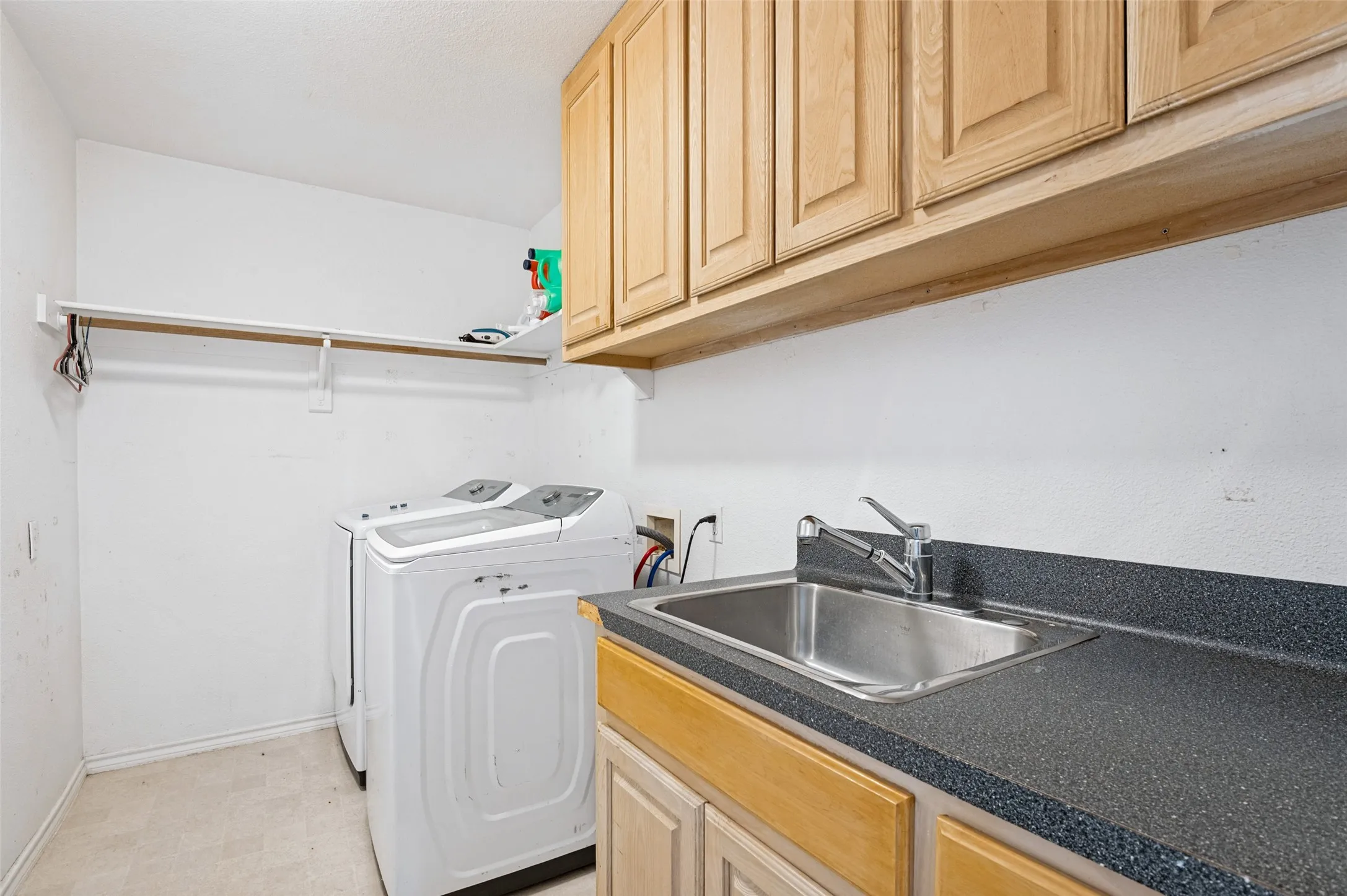 A spacious laundry room offers added convenience with a utility sink and built-in cabinetry, providing plenty of storage and workspace to keep everyday household tasks organized.