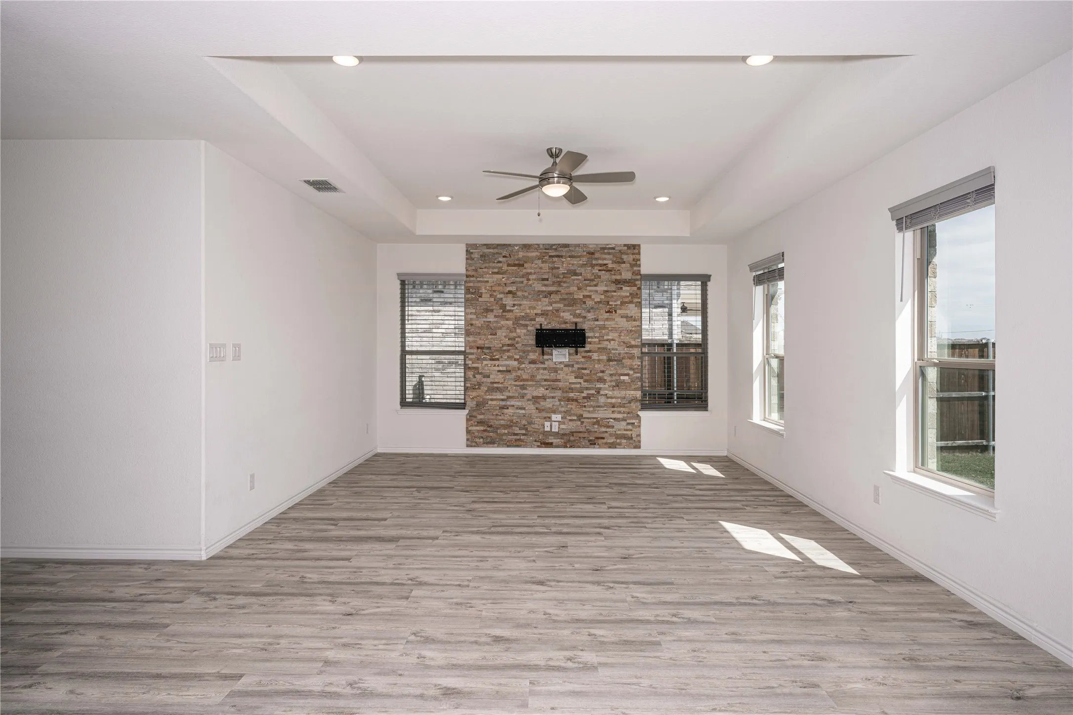 Living room with light hardwood / wood-style flooring, ceiling fan, and
tray ceiling