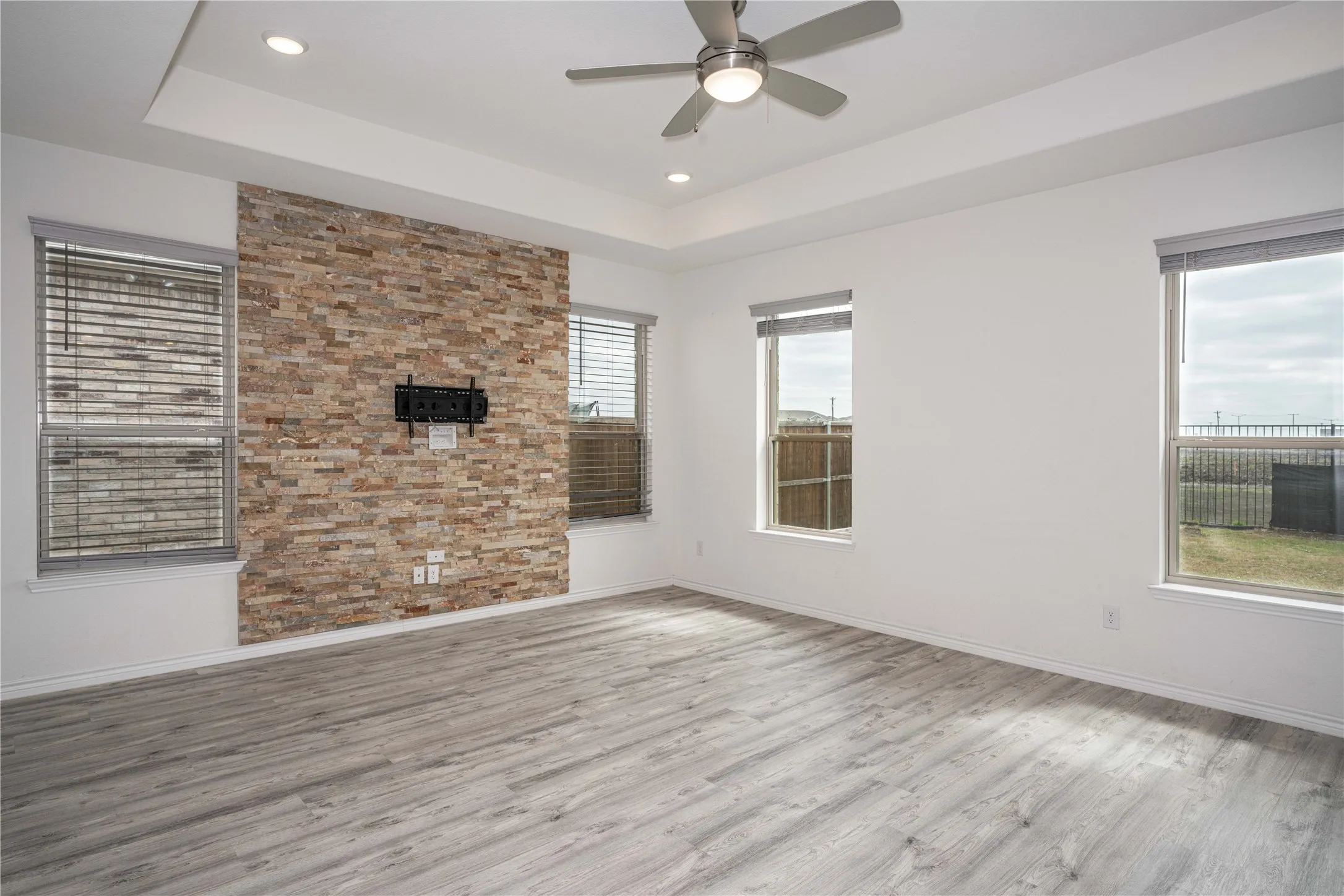 Living room with ceiling fan, a tray ceiling, and light hardwood / wood-style floors