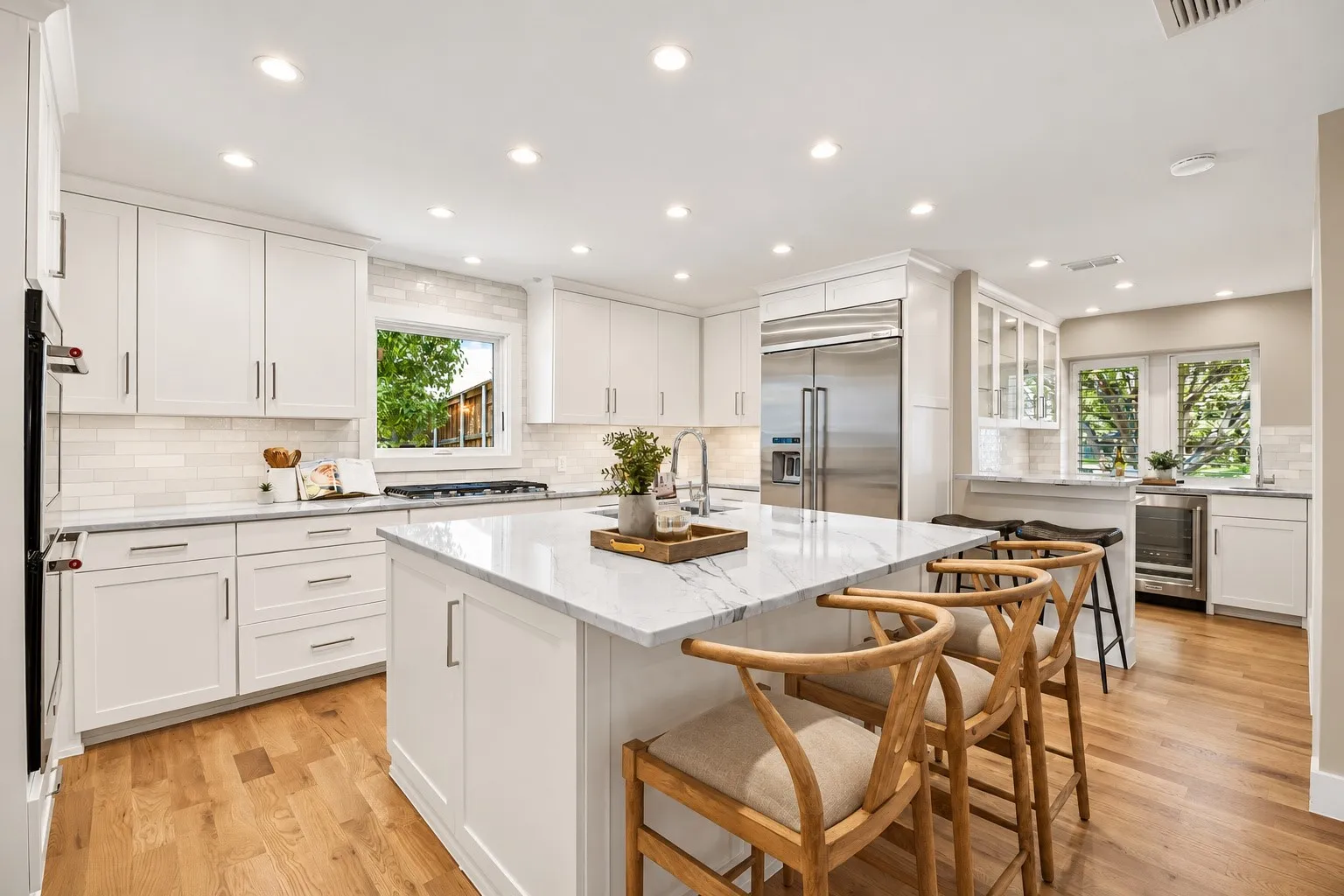 Open kitchen featuring beautiful yard view and solid wood cabinetry, stone countertops, stainless steel appliances, recessed lighting, and oak flooring