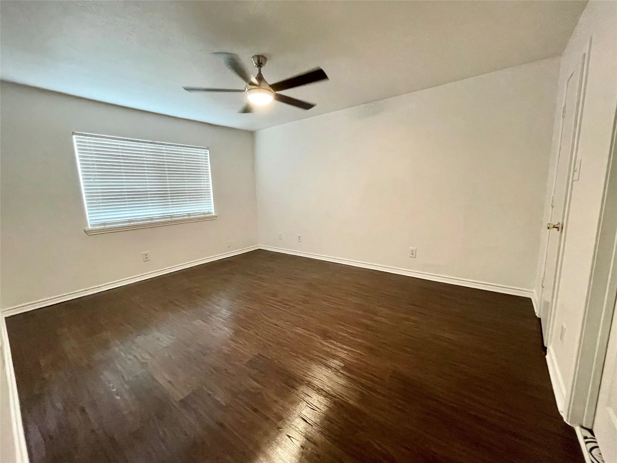 Wood-finish flooring, ceiling fan with integrated lighting, and window with horizontal blinds