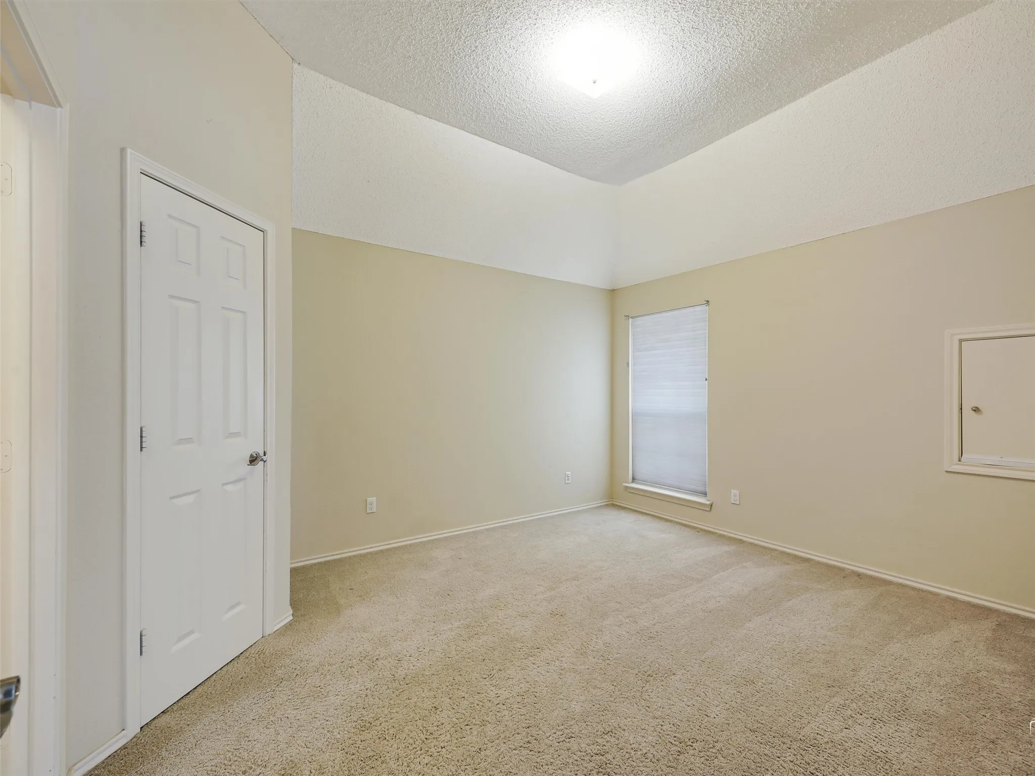 Vaulted ceilings, neutral wall color, wall-to-wall carpeting, single-panel interior door, and window with built-in blinds