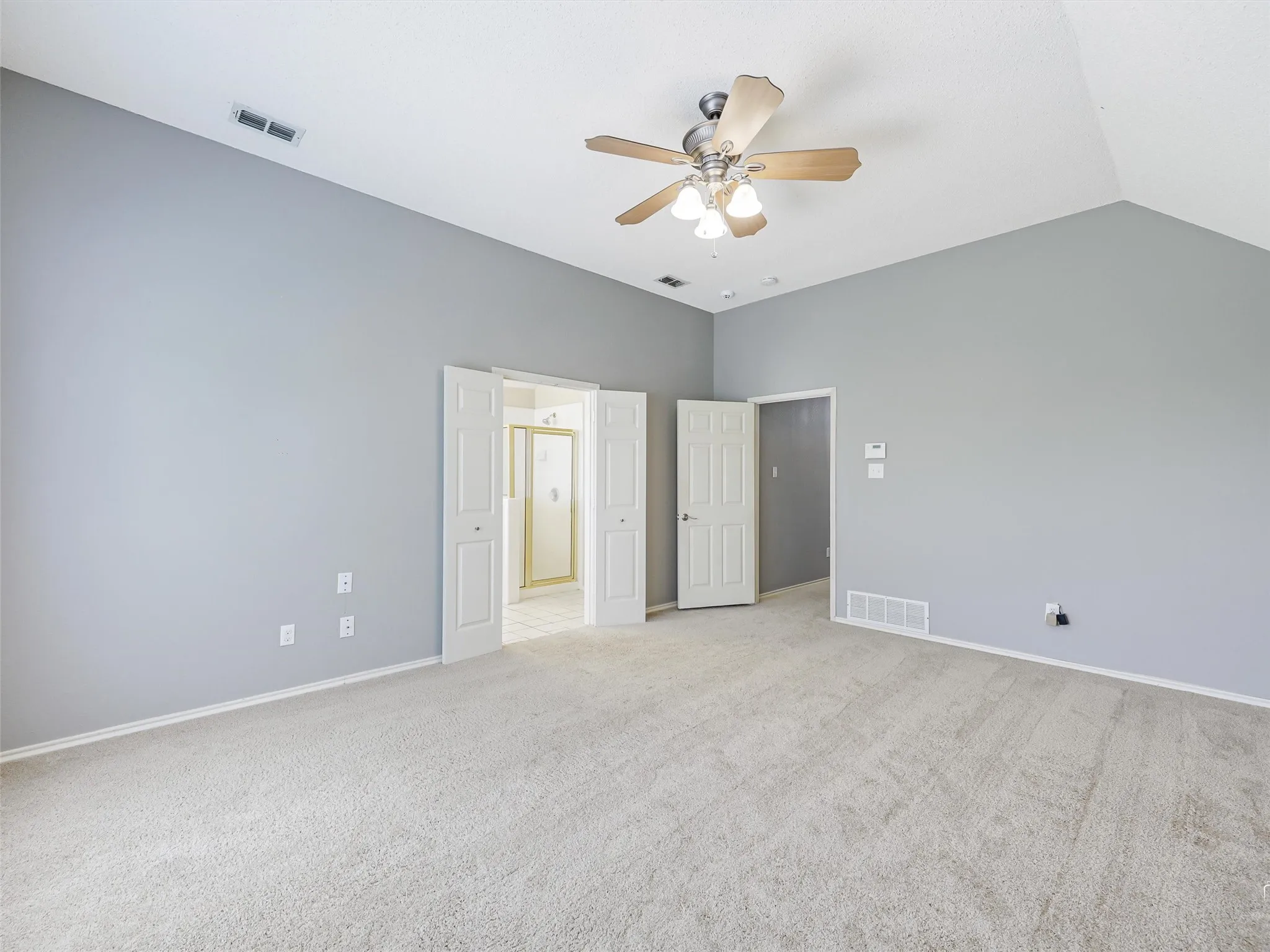 Room featuring vaulted ceilings, carpeted flooring, neutral wall paint, and a ceiling fan with integrated lighting