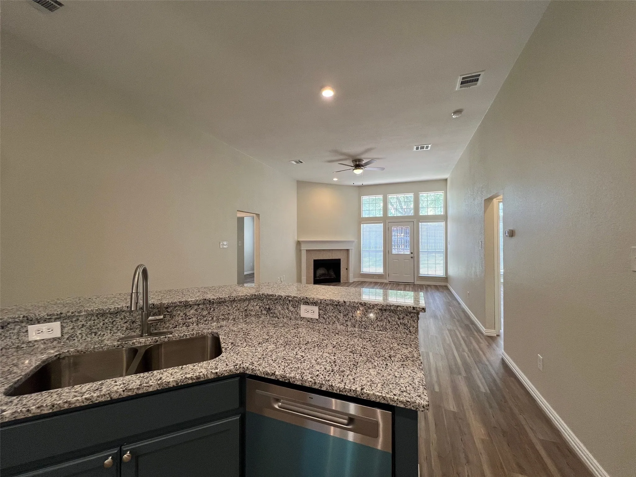 Kitchen featuring a speckled stone countertop, stainless steel dual-basin sink with a gooseneck faucet, and dark-toned cabinetry