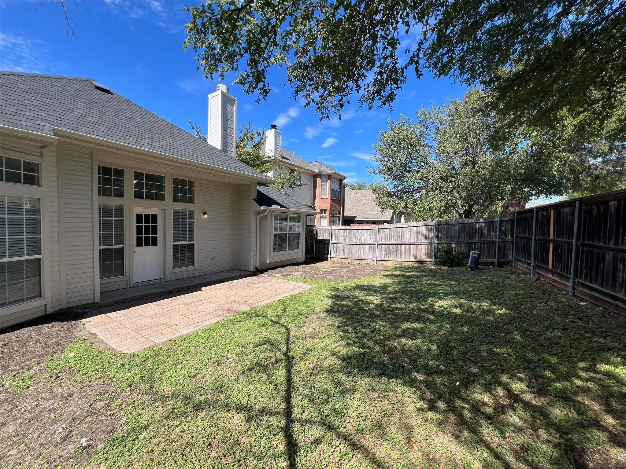Rear exterior featuring a concrete patio, siding facade, multi-pane windows, and wood privacy fencing