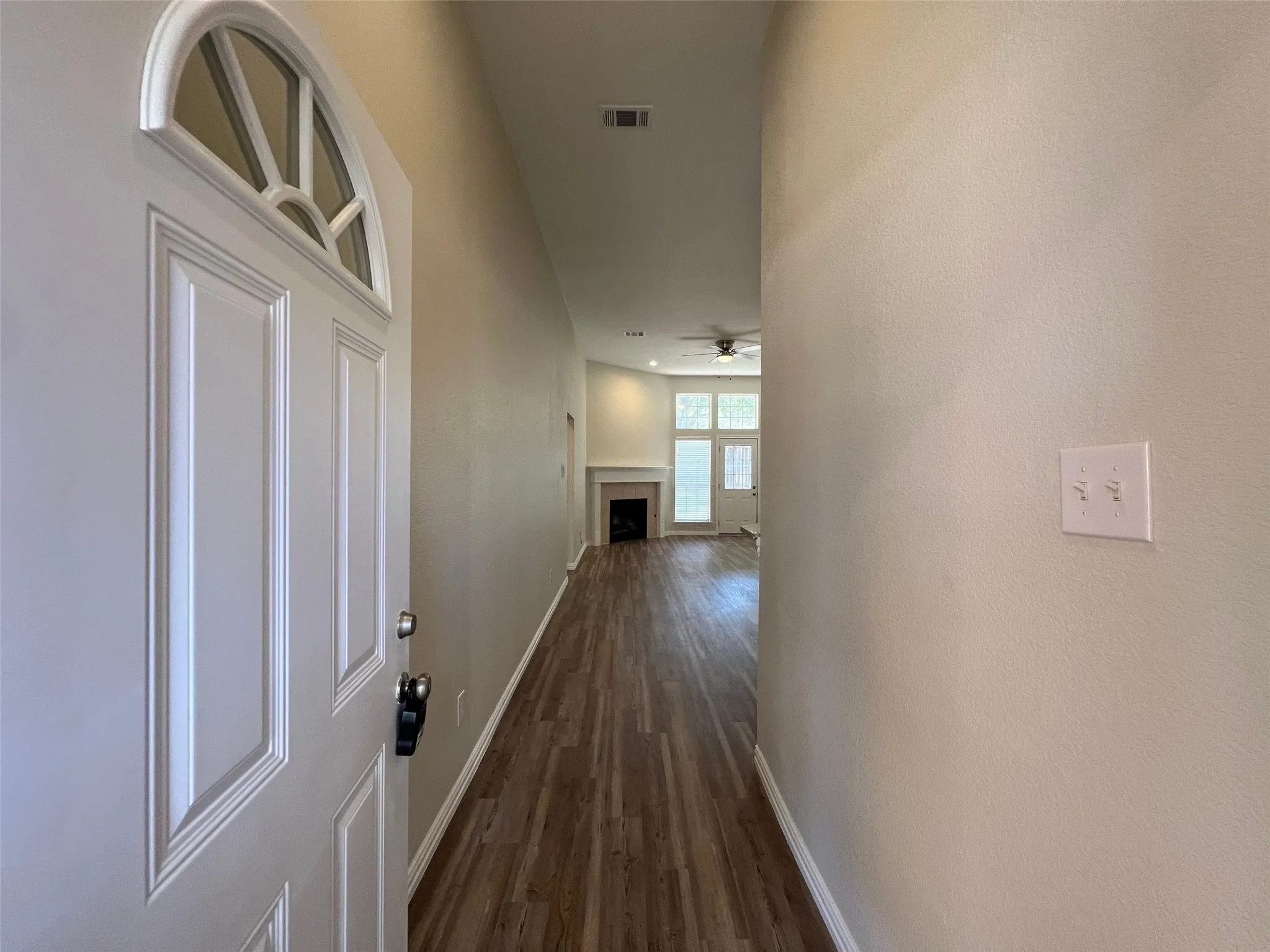 Entryway featuring wood-finish flooring, a paneled front door with a semi-circular transom window, and a built-in fireplace