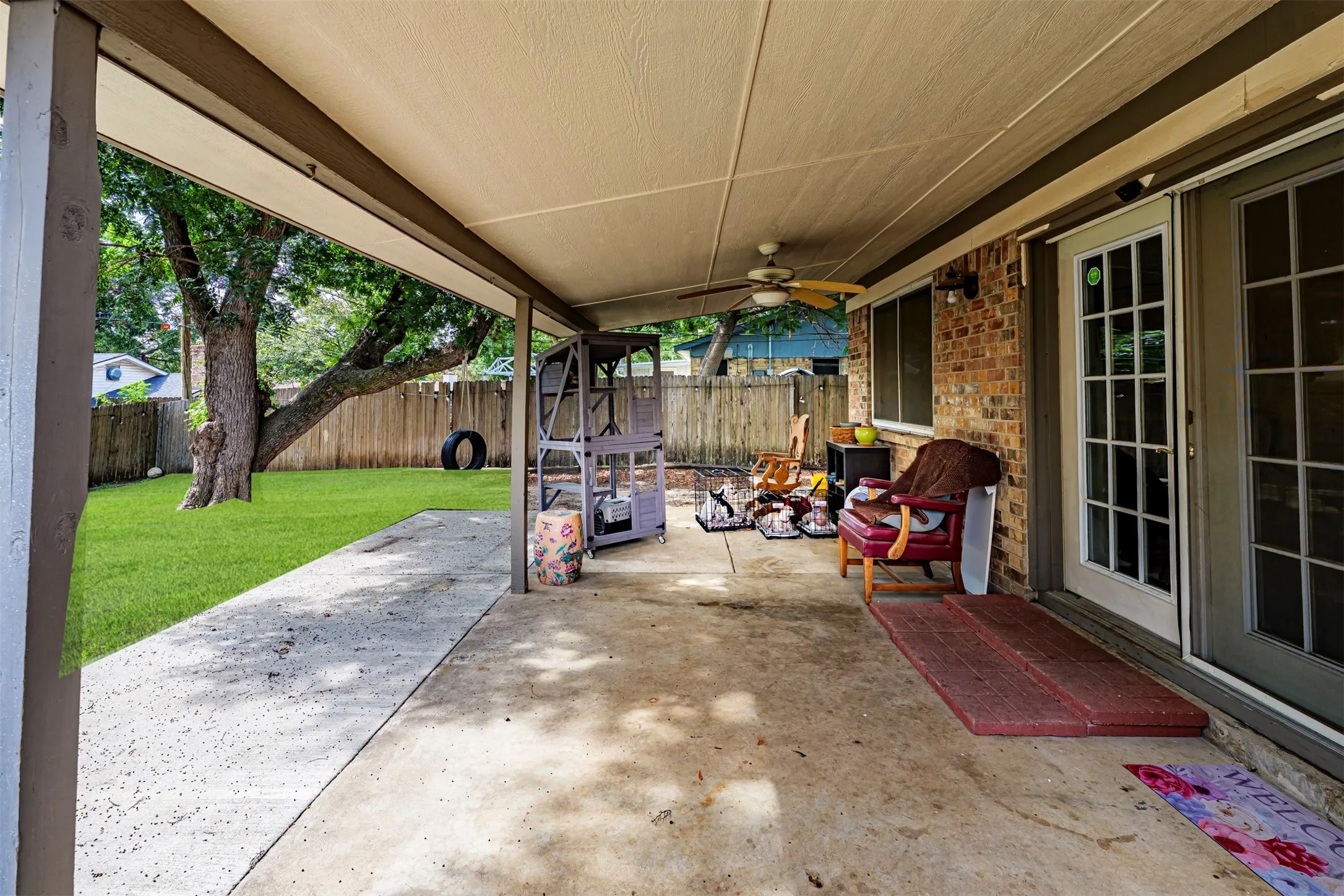 Covered concrete patio featuring a ceiling fan, brick exterior siding, and french door access