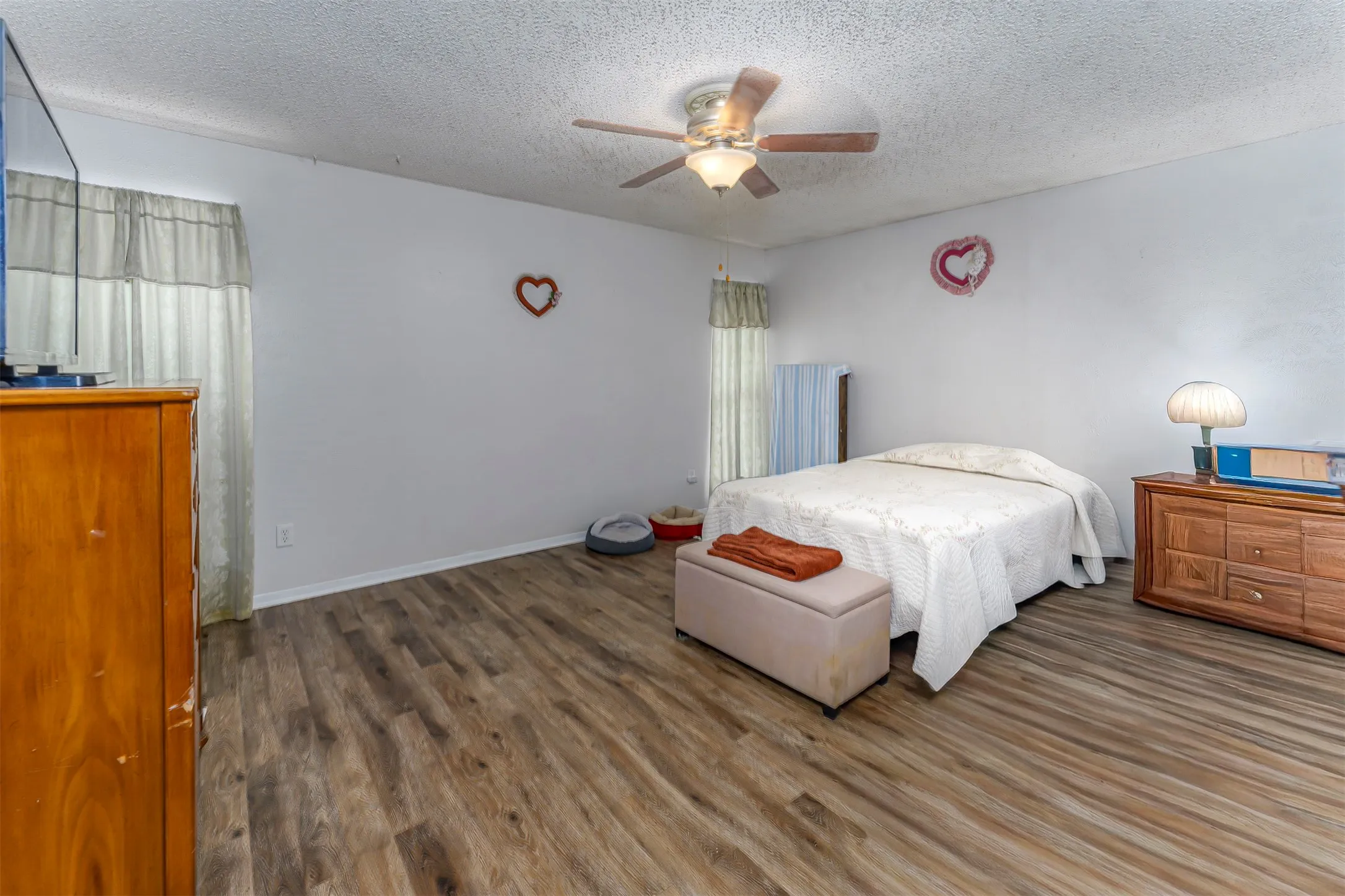 Wood-finish flooring, ceiling fan with integrated lighting, and dual windows with vertical blinds