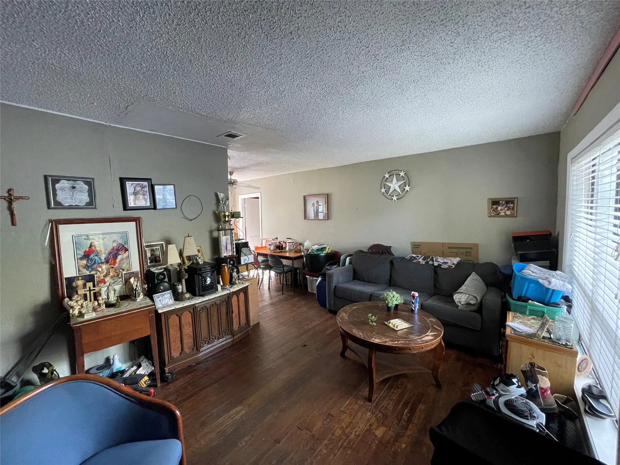 Interior space featuring wood-finish flooring, a textured ceiling, and a window with horizontal blinds