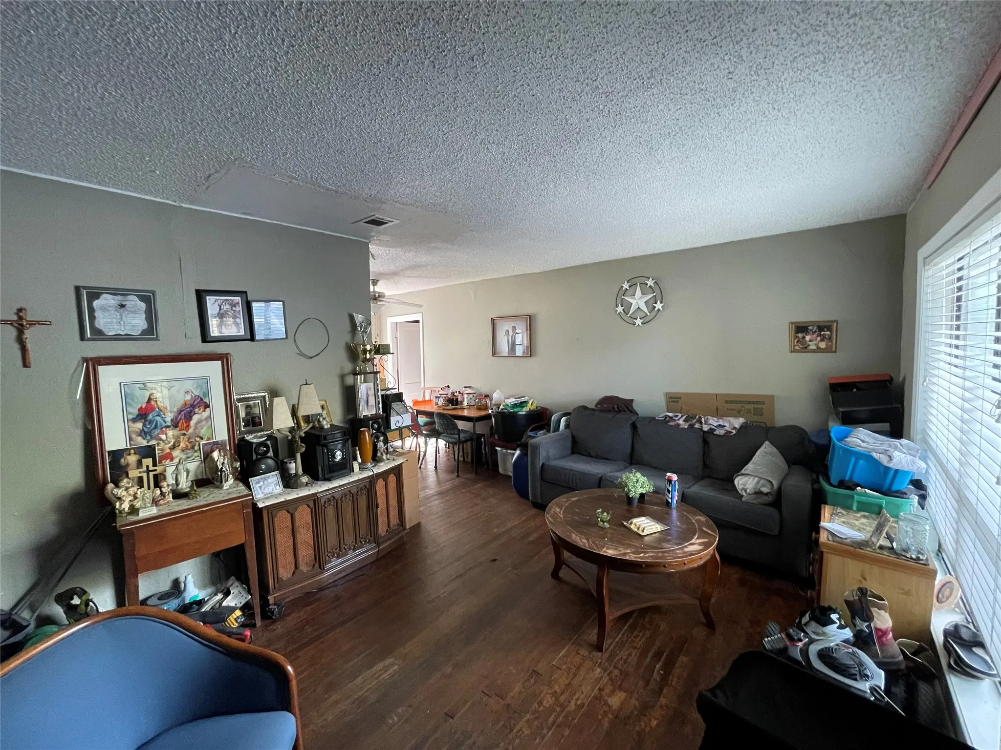 Living space featuring dark wood-finish flooring and windows fitted with horizontal blinds