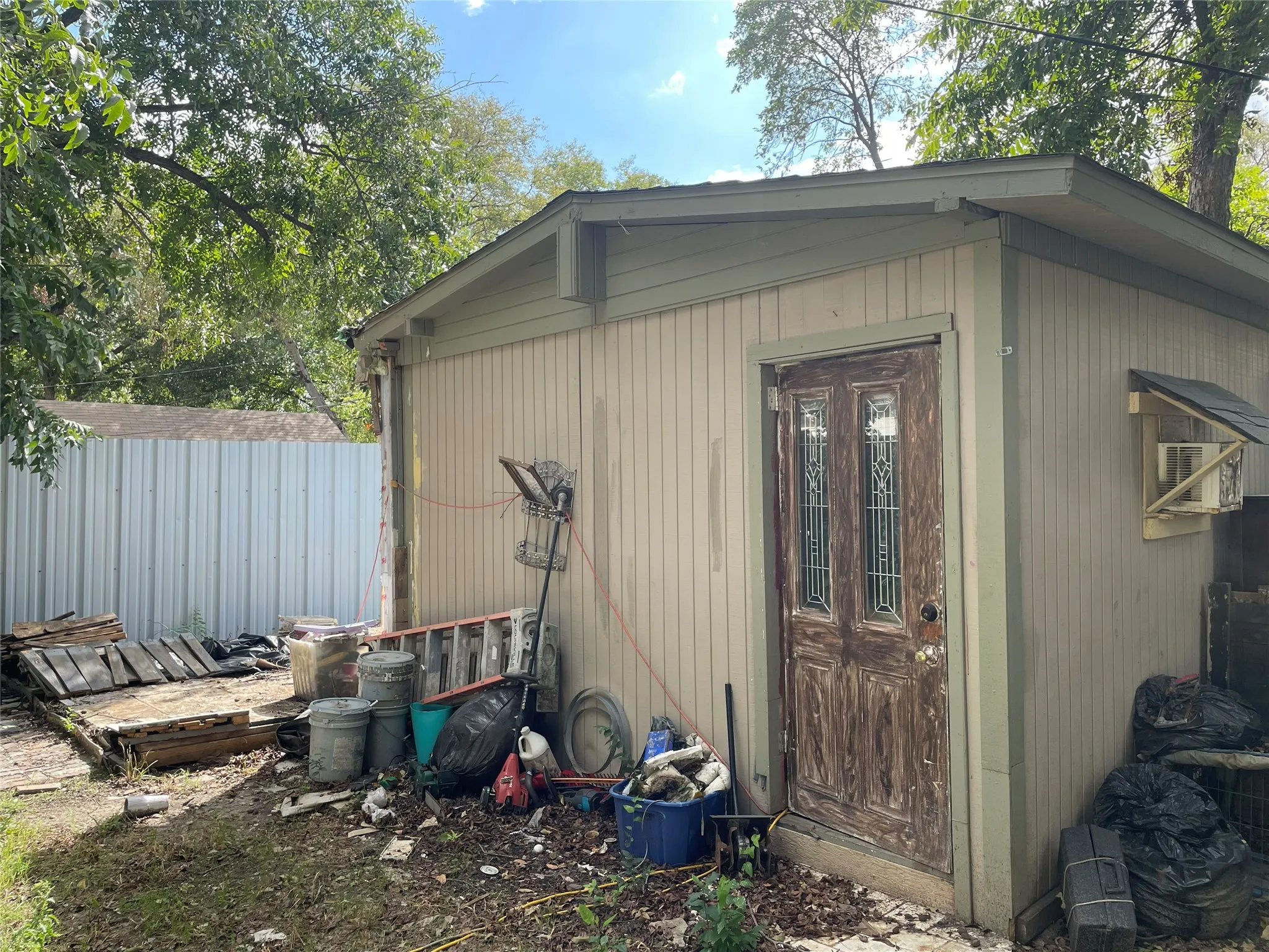 Exterior structure with vertical wood siding and a door featuring glass panel inserts