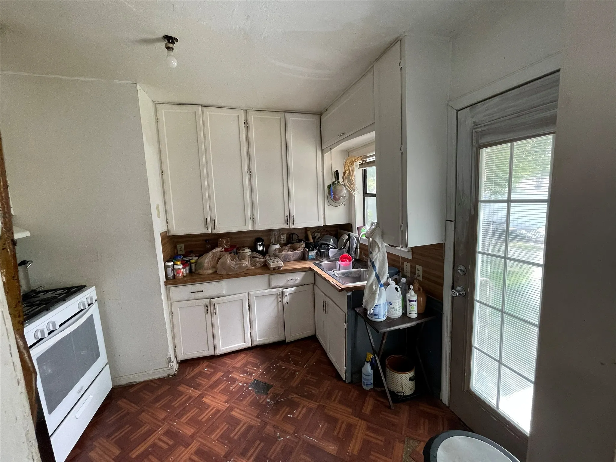 Kitchen featuring white cabinetry, wood-finish parquet flooring, a stainless steel double-basin sink, and a glass-paneled exterior door