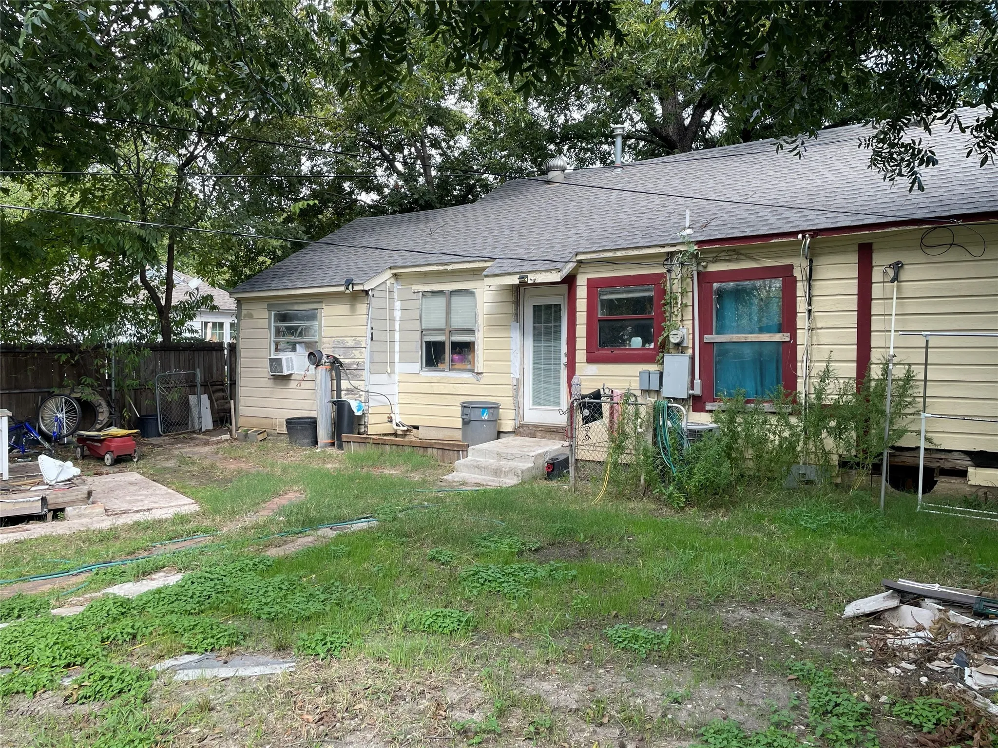 Single-story exterior featuring wood lap siding, asphalt shingle roofing, and mature perimeter trees