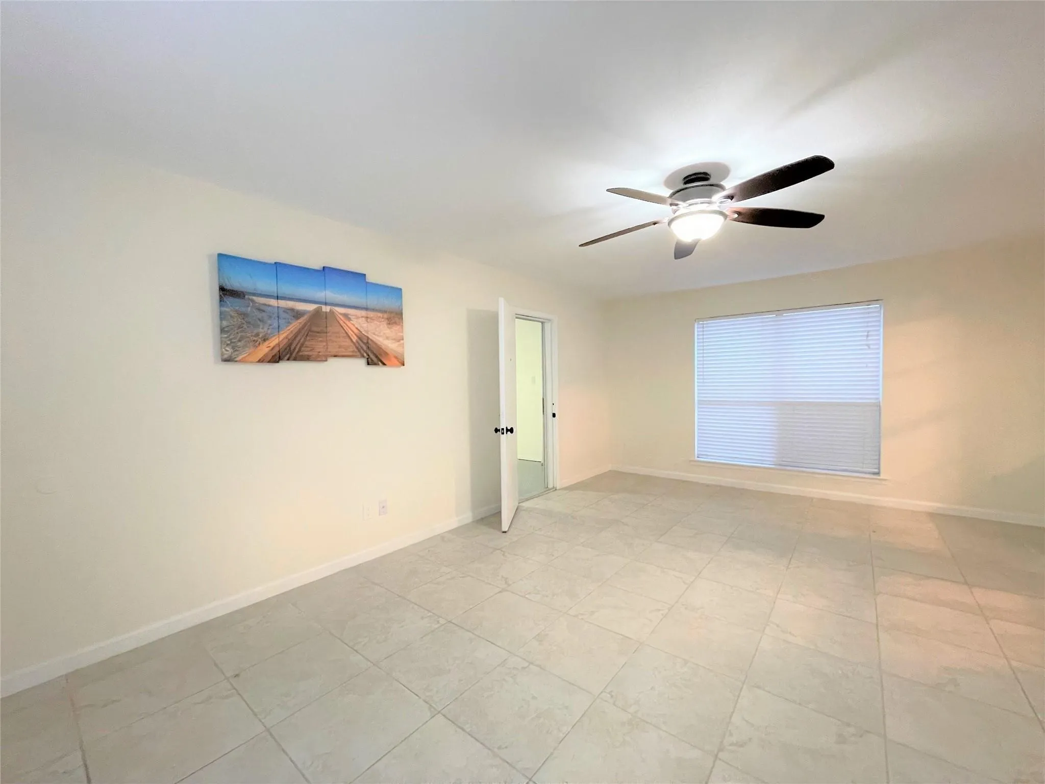 Neutral-toned ceramic tile flooring, ceiling fan with integrated light fixture, and single-pane window with horizontal blinds