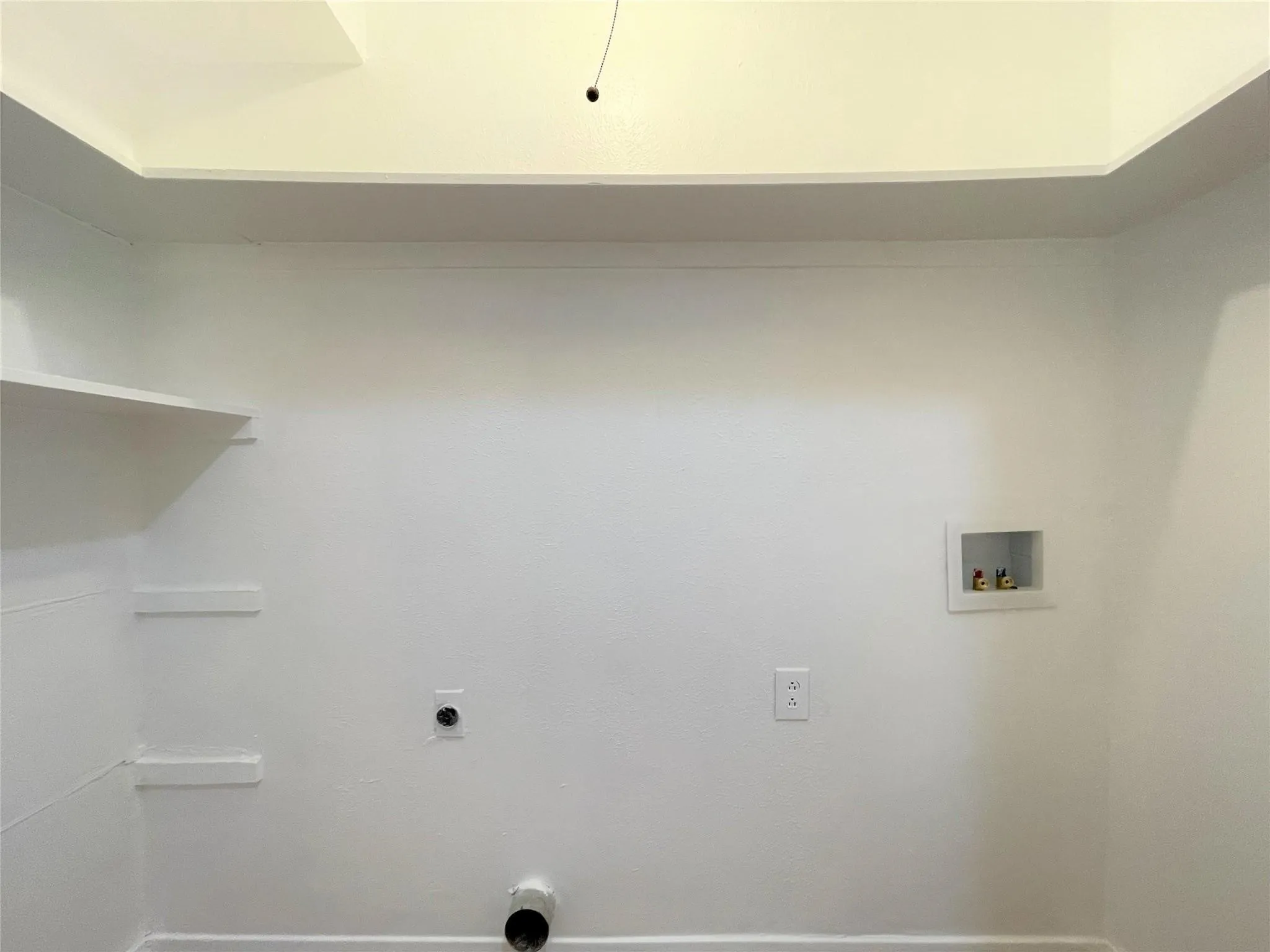Laundry space featuring built-in shelving, a recessed utility box, and integrated wall hookups