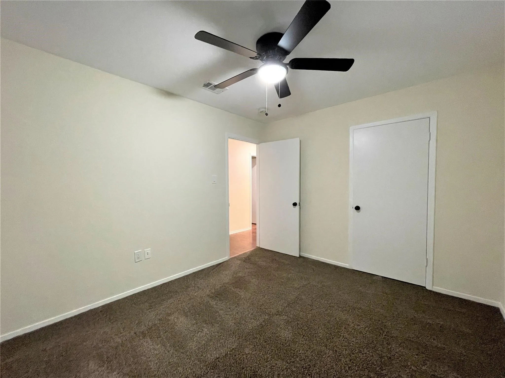 Room featuring neutral wall tones, carpeted flooring, and a ceiling fan with integrated lighting