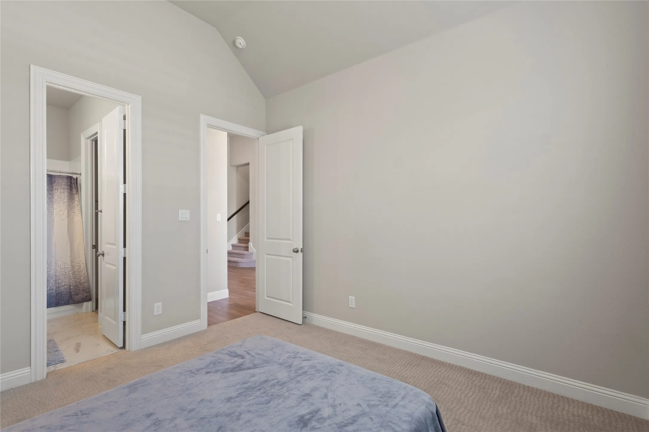 Interior room featuring vaulted ceilings, neutral wall paint, carpeted flooring, and two-panel interior doors