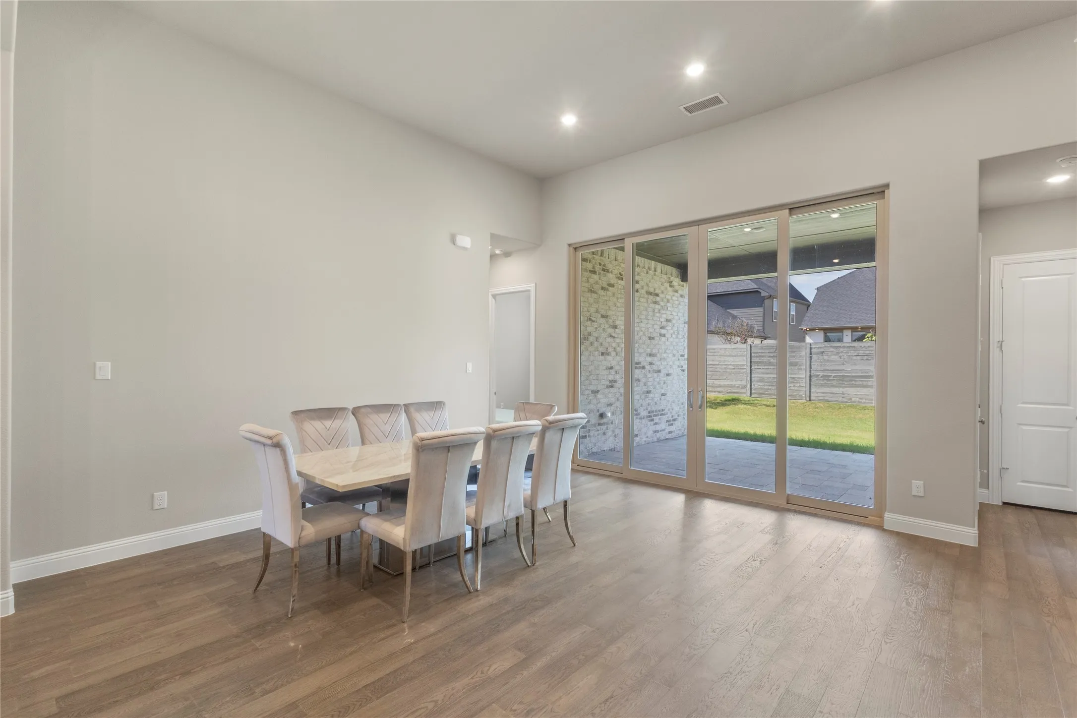High ceilings with recessed lighting, wood-finish flooring, and expansive multi-panel sliding glass doors providing access to a covered patio