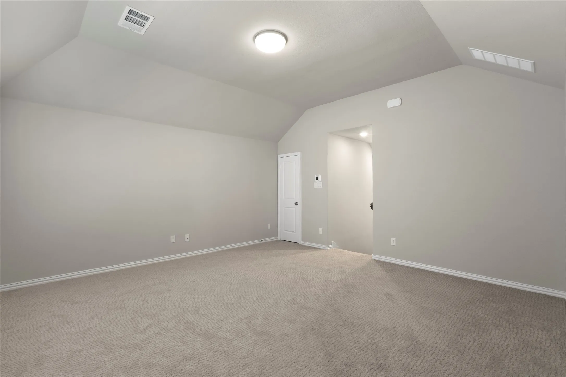 Vaulted ceiling, neutral wall tones, and neutral-toned carpeting
