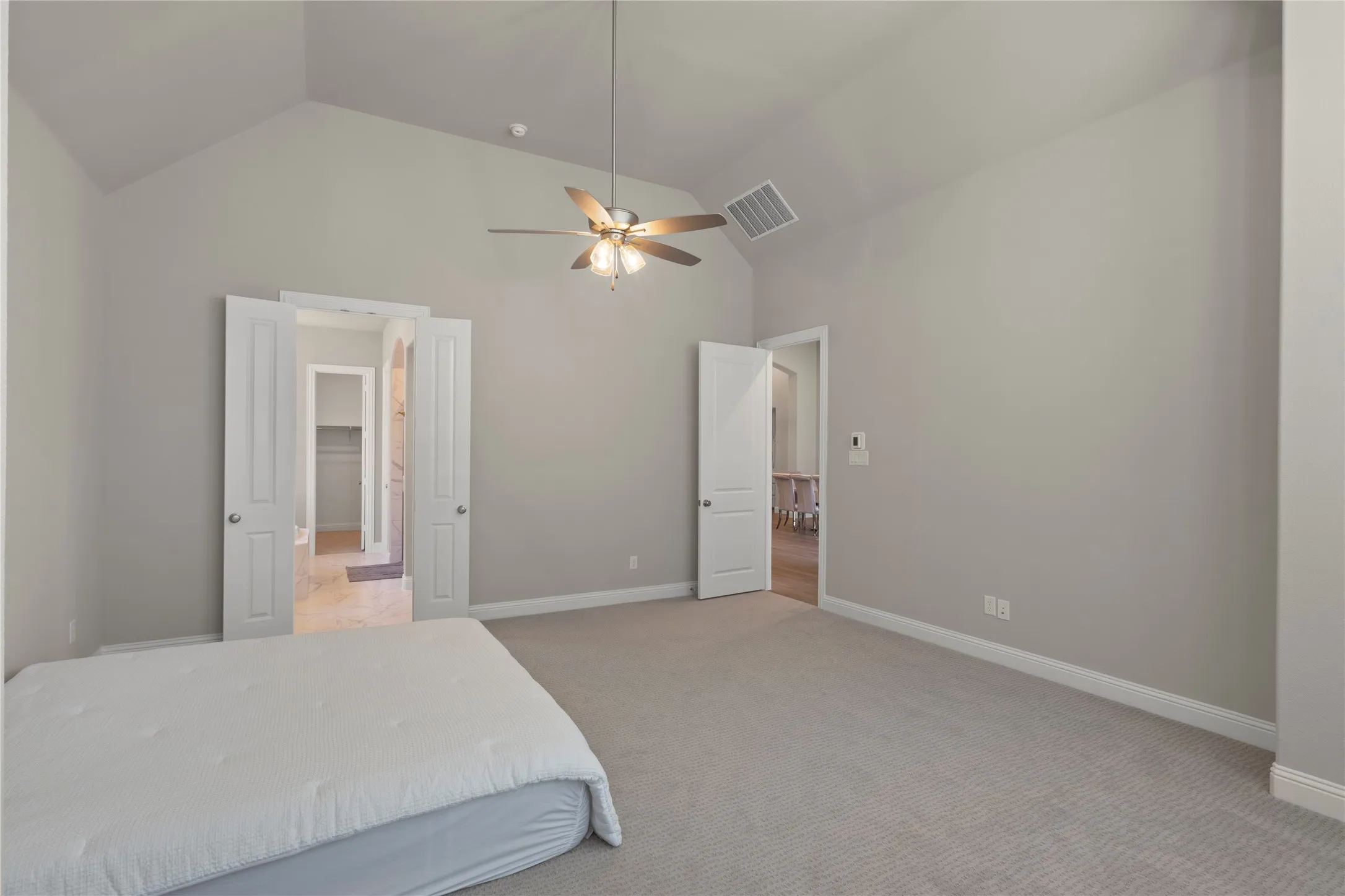 Vaulted ceiling featuring a central multi-blade ceiling fan with integrated light fixture, carpeted flooring, and neutral wall tones