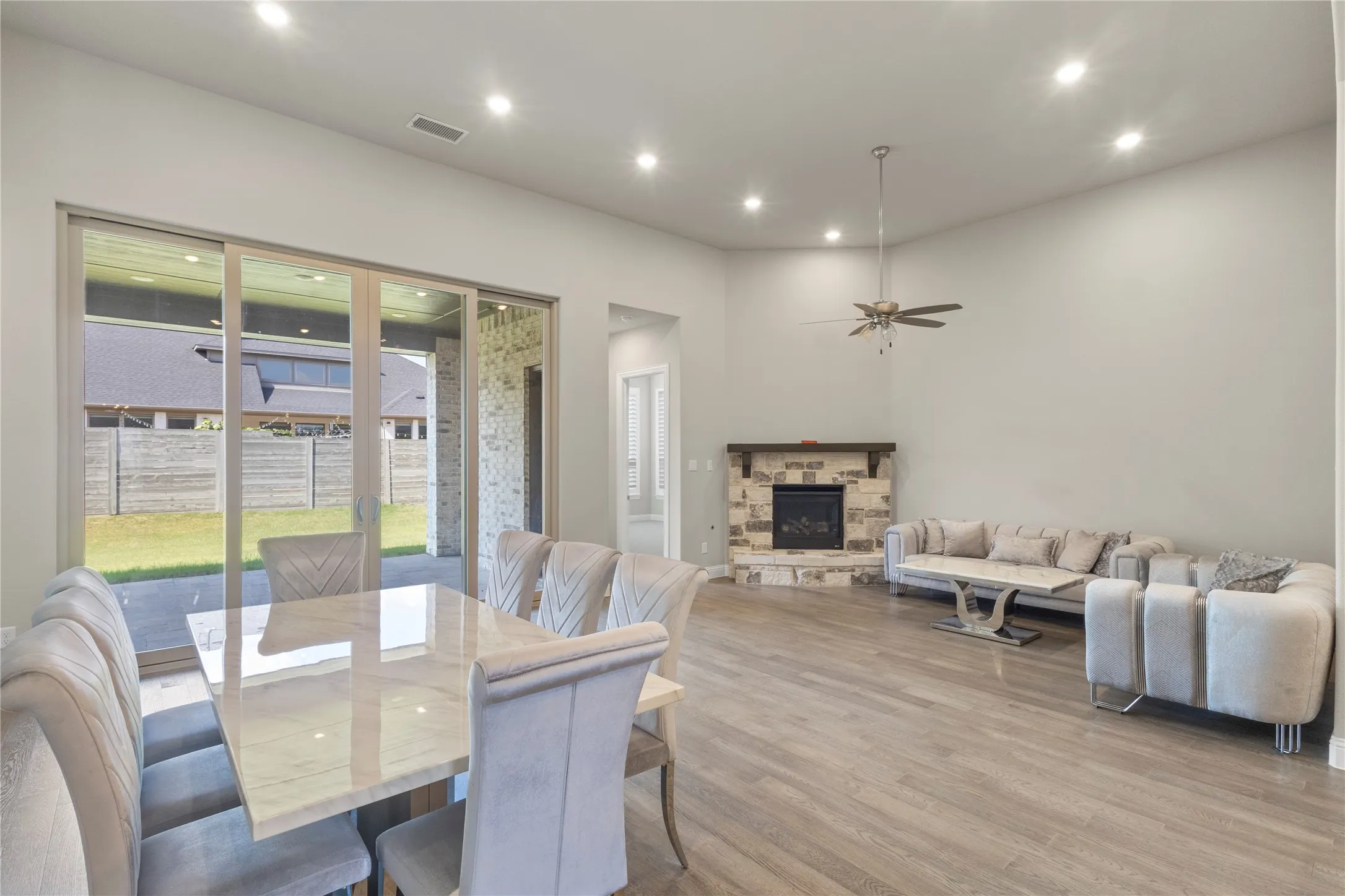 Open floor plan featuring wood-finish flooring, recessed lighting, corner stone fireplace with a wood mantel, and expansive sliding glass doors