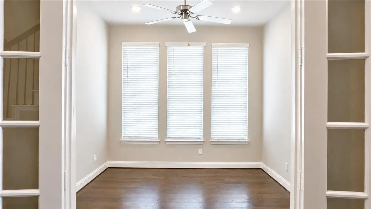 Room featuring three large windows, wood-finish flooring, recessed lighting, a brushed-nickel ceiling fan, and French doors with glass panes
