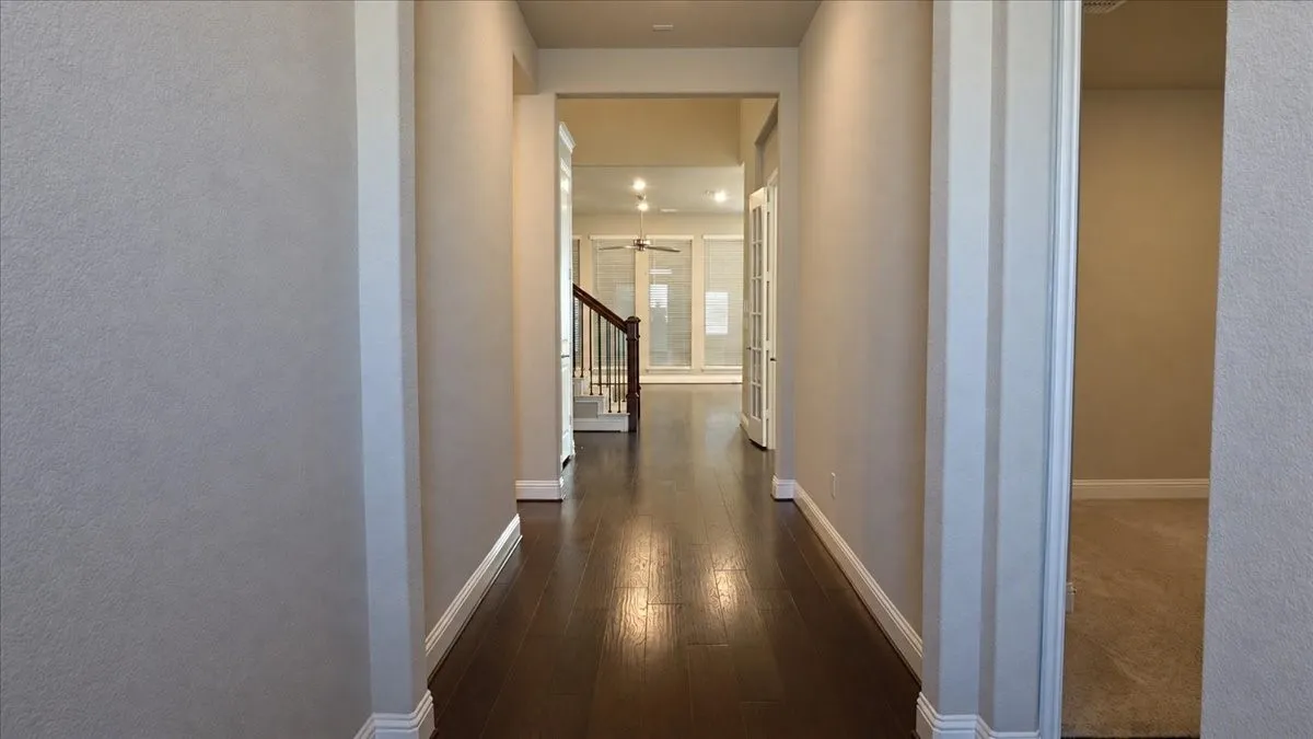 Interior hallway featuring wood-finish flooring, recessed lighting, and a staircase with a wooden handrail