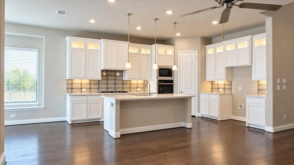 Kitchen featuring white cabinetry with glass-front uppers, a center island with a built-in sink, wood-finish flooring, tiled backsplash, and recessed lighting