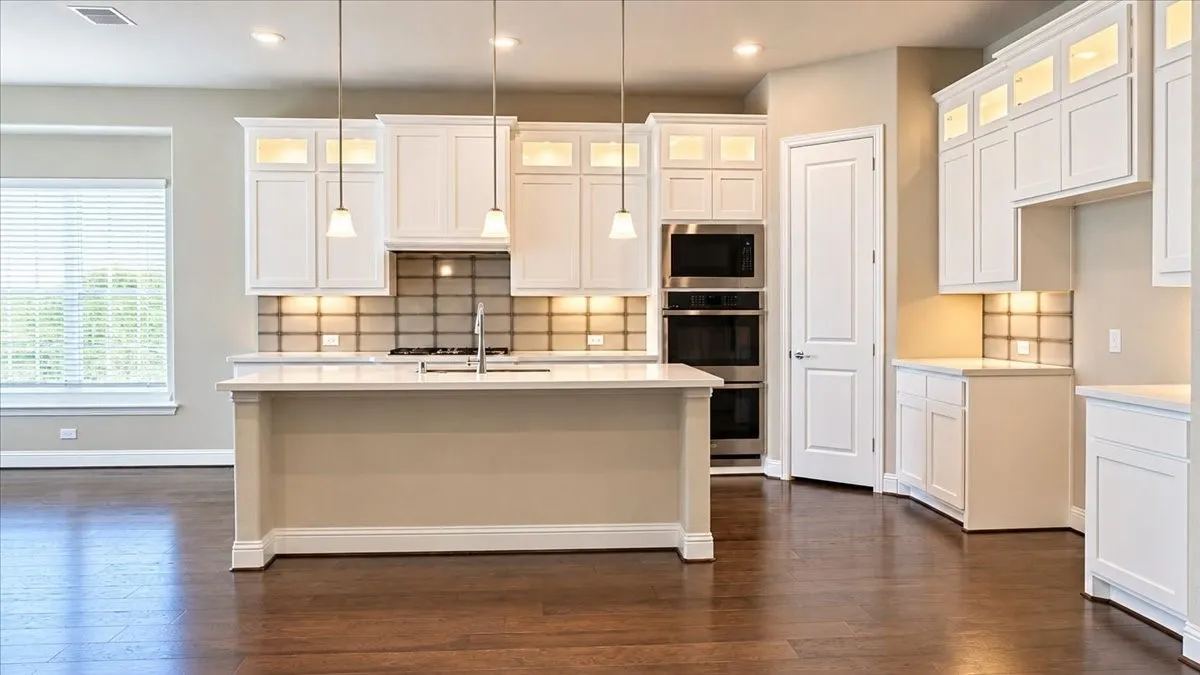 Kitchen featuring white cabinetry, center island with stone countertop, tile backsplash, stainless steel double wall ovens, and wood-finish flooring
