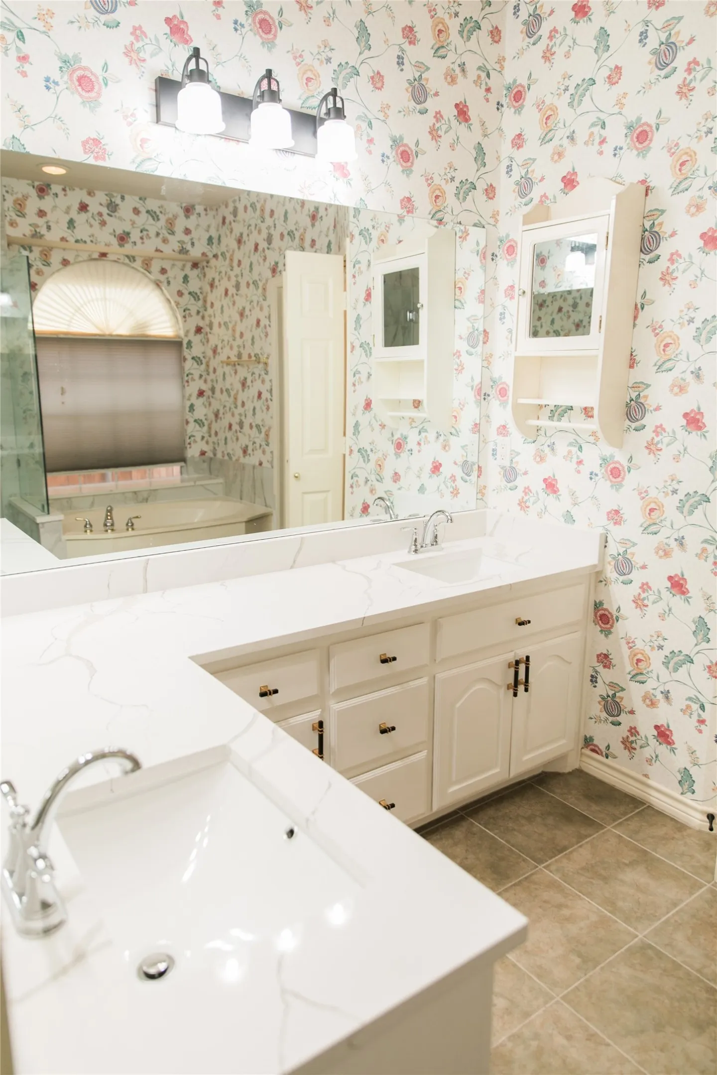 Double vanity featuring quartz countertops, undermount sinks, chrome fixtures, built-in cabinetry, and wall-mounted storage units