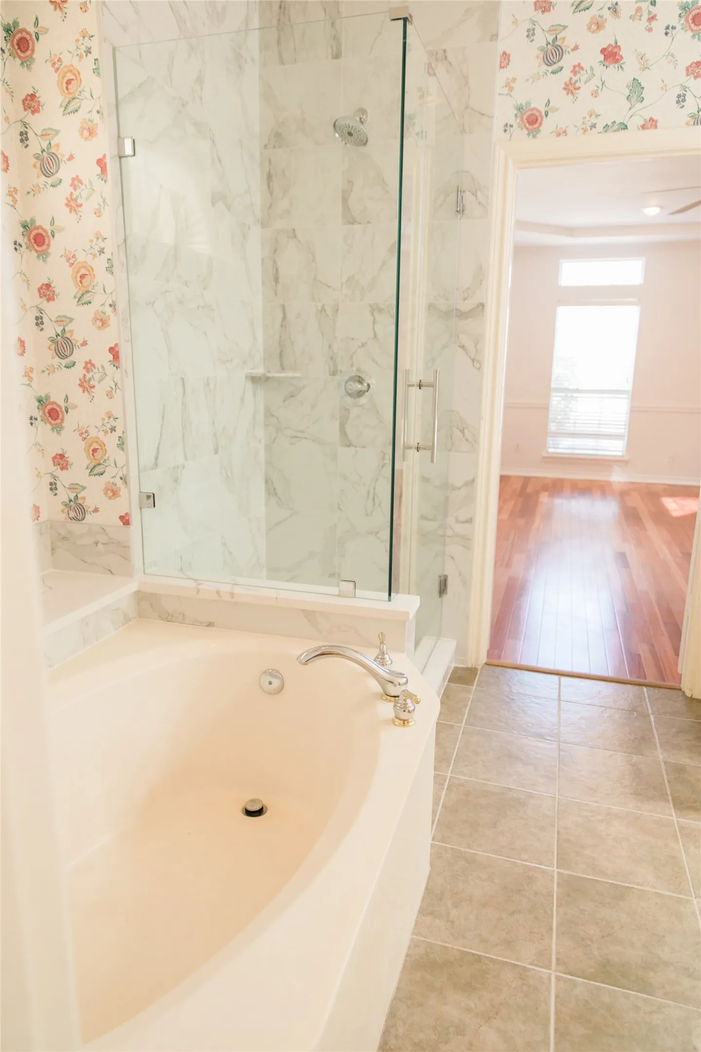 Oval soaking tub with deck-mounted faucet, walk-in shower with glass enclosure, and tile flooring