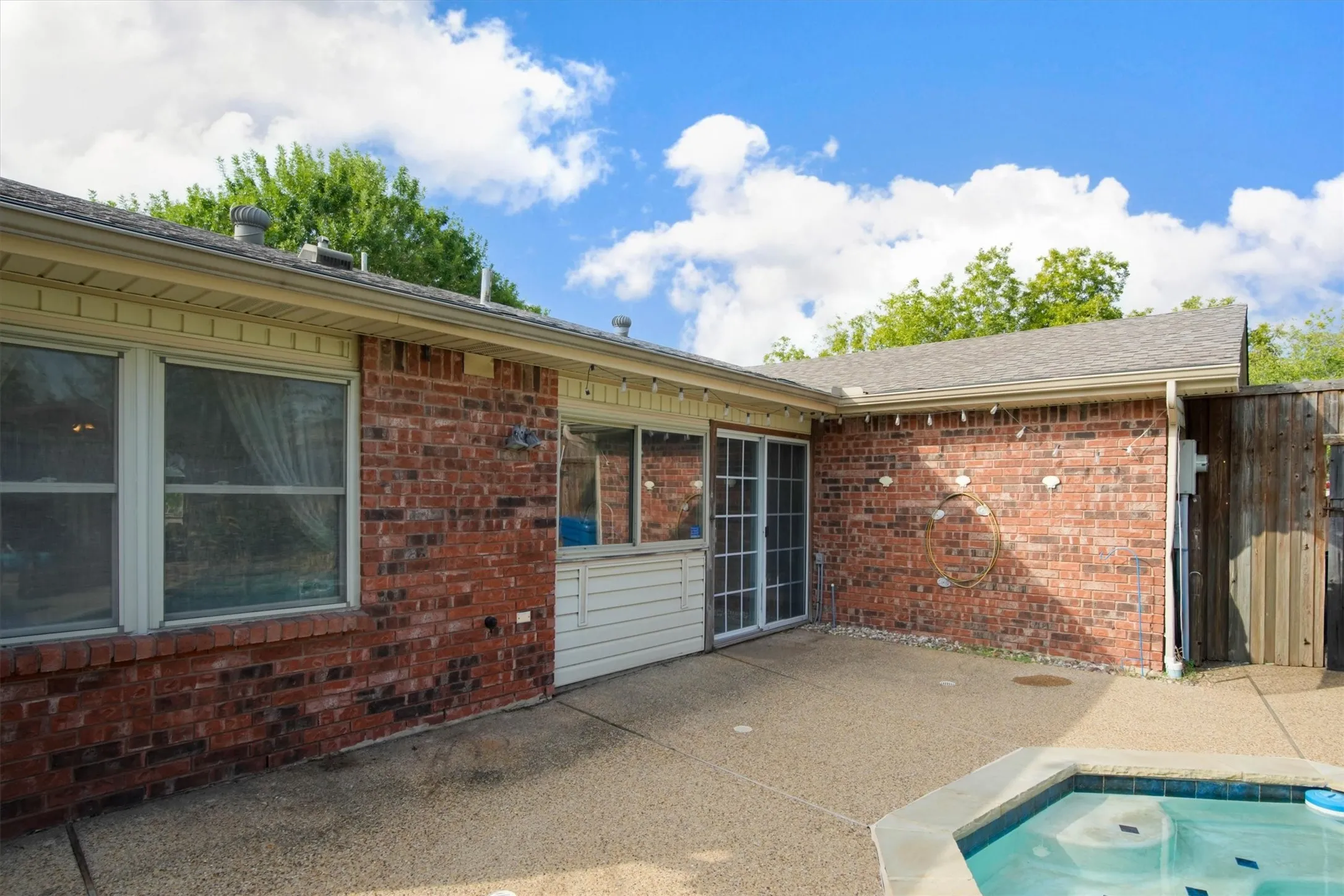 Exterior brick facade featuring a concrete patio, and double paned sliding glass doors
