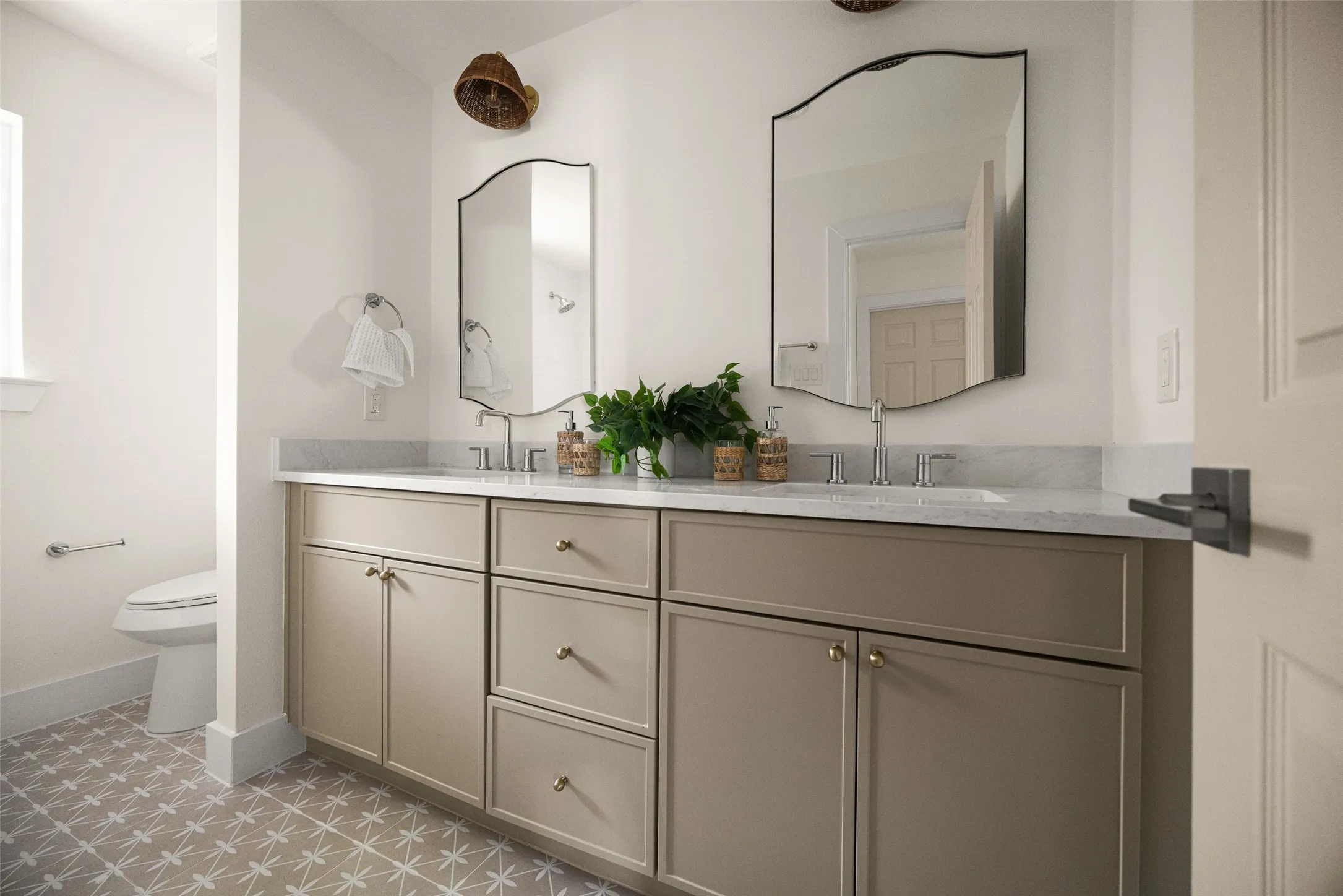 Fully updated secondary bathroom featuring a double vanity, refined finishes, decorative tile flooring, and a bright tub-shower surround with clean, timeless tilework.