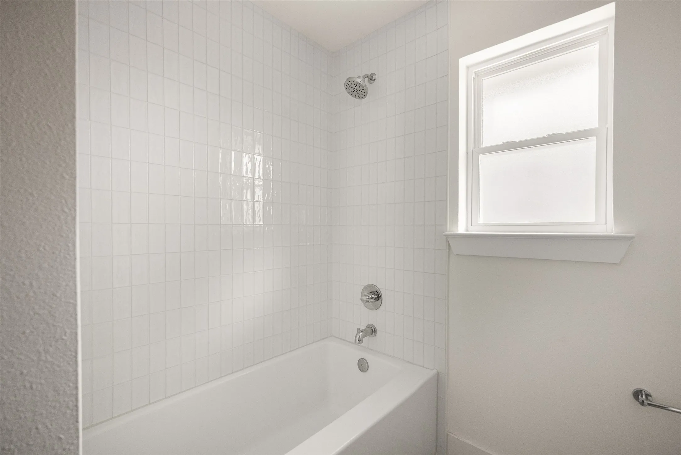 Fully updated secondary bathroom featuring a double vanity, refined finishes, decorative tile flooring, and a bright tub-shower surround with clean, timeless tilework.