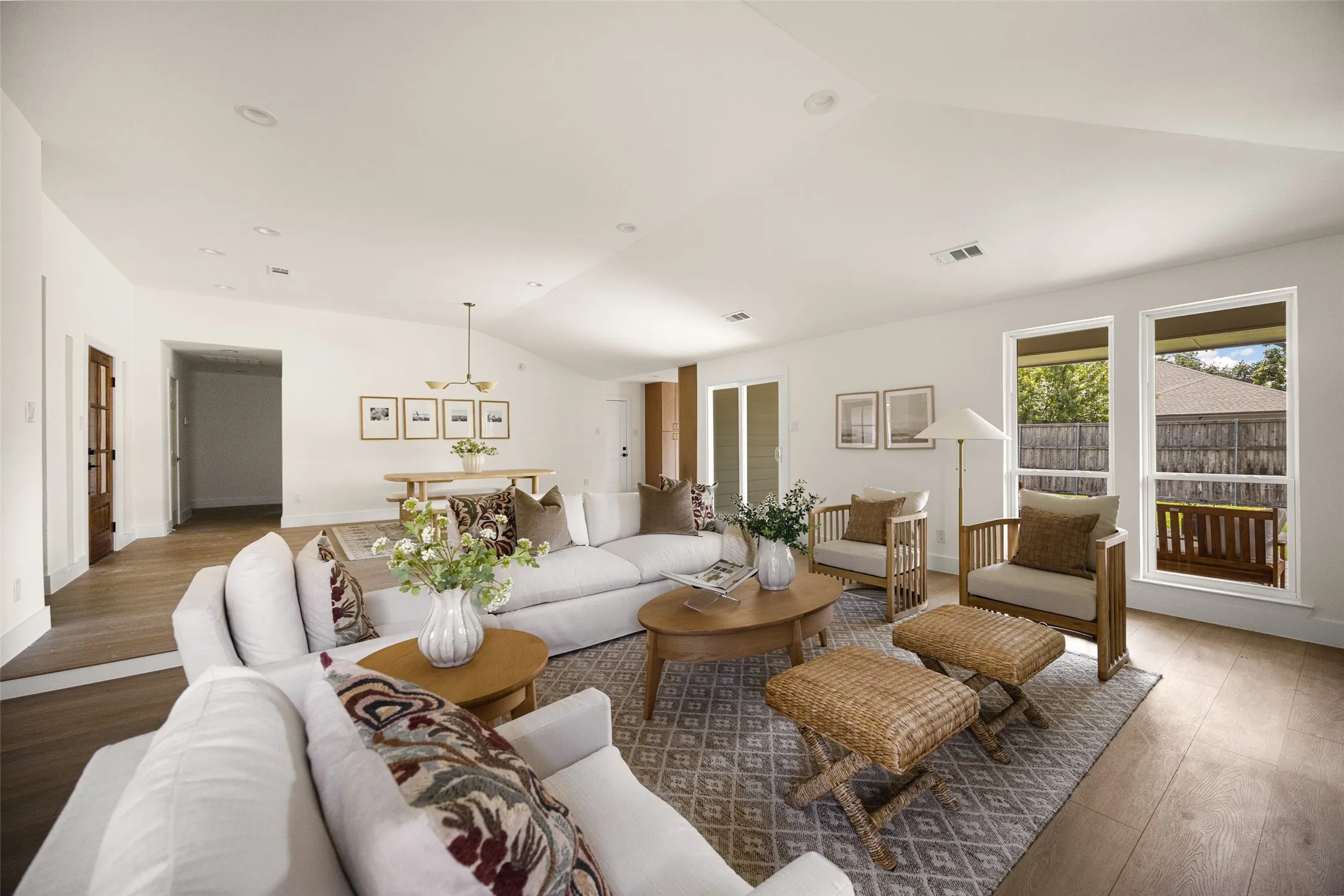 Bright and inviting living area featuring vaulted ceilings, a beautifully updated brick fireplace with wood mantel, built-in shelving, and large windows overlooking the backyard.